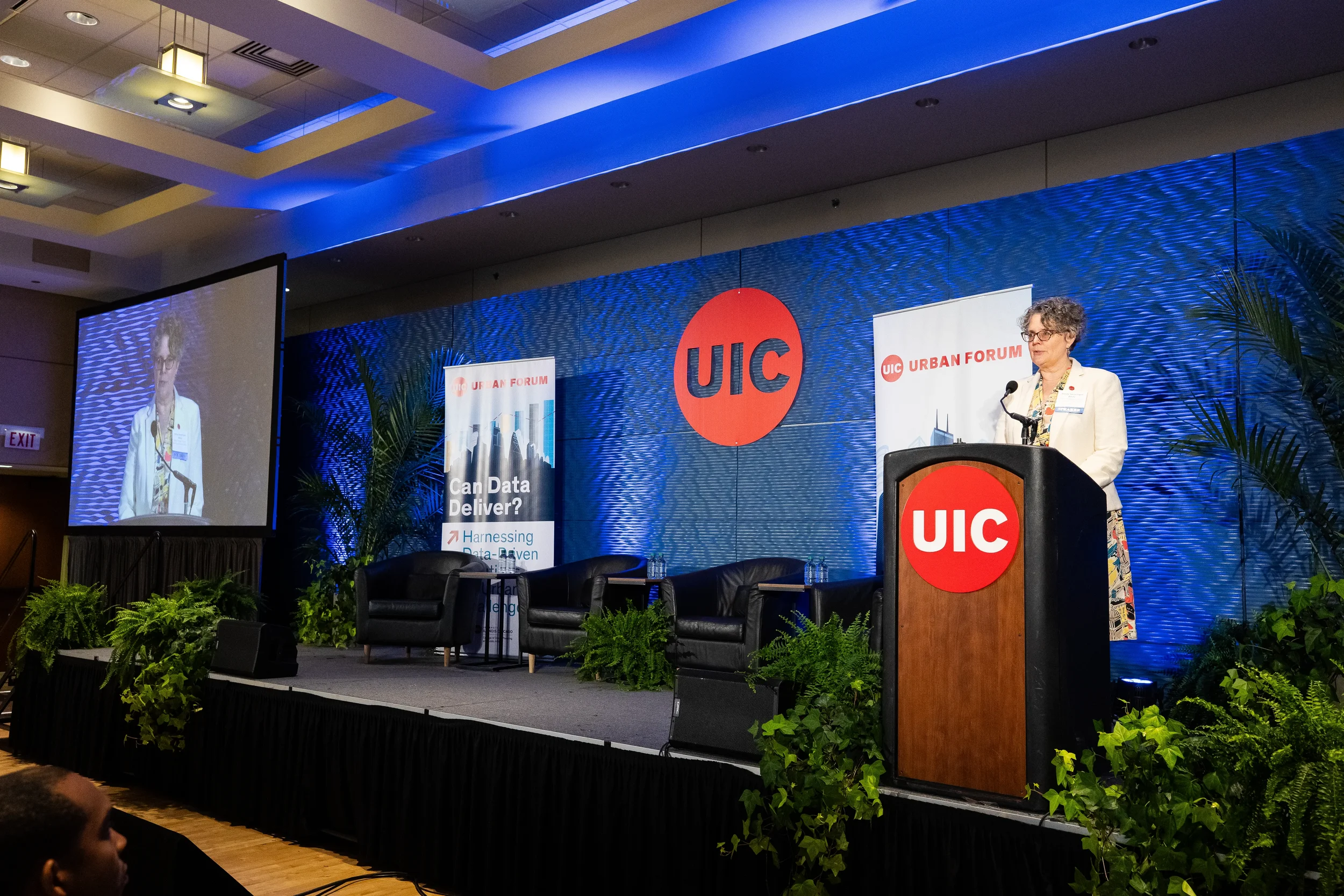Speaker in white blazer addresses audience from podium at Orlando industry conference