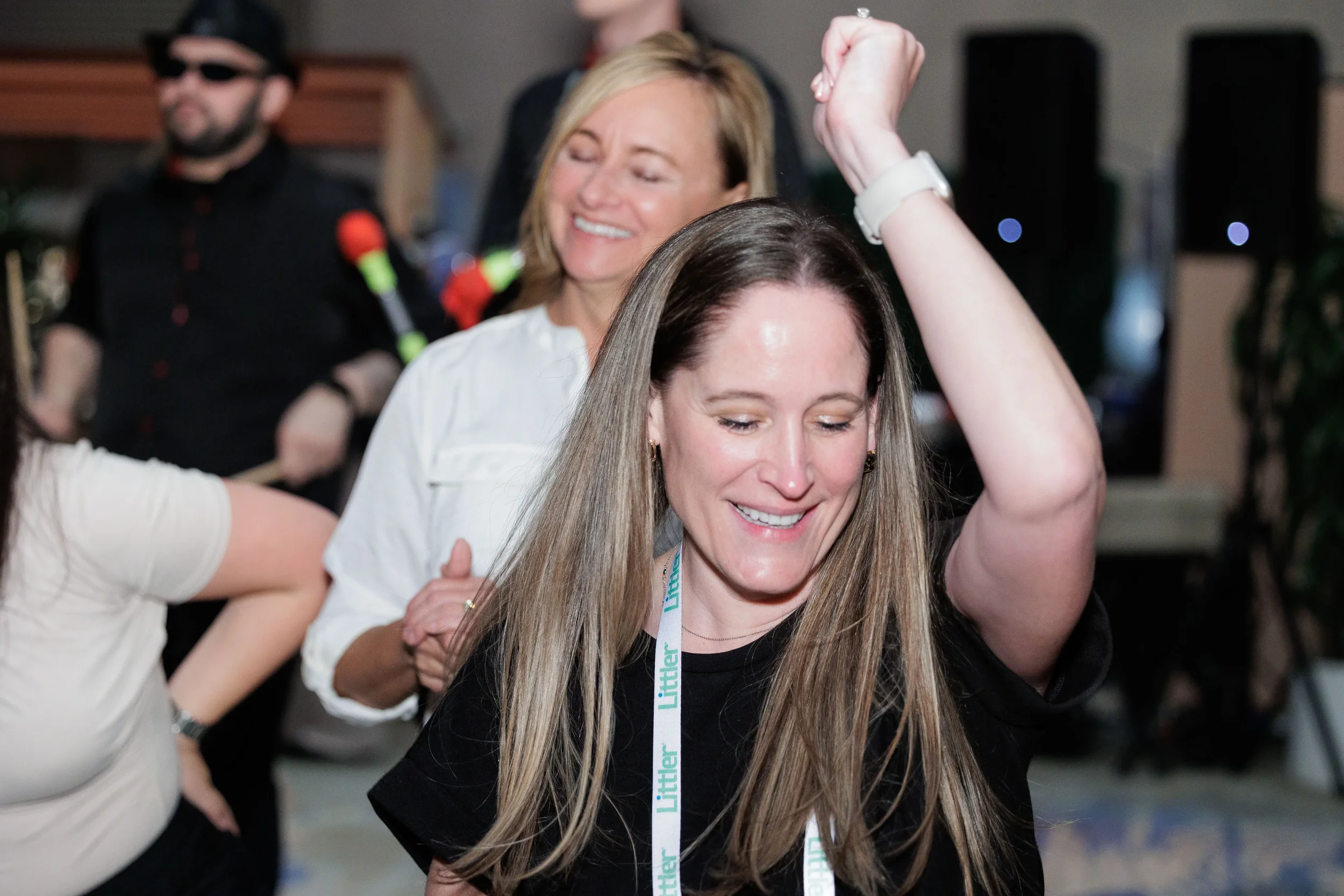 Attendee with lanyard dances with arm raised near live band at Orlando corporate conference reception