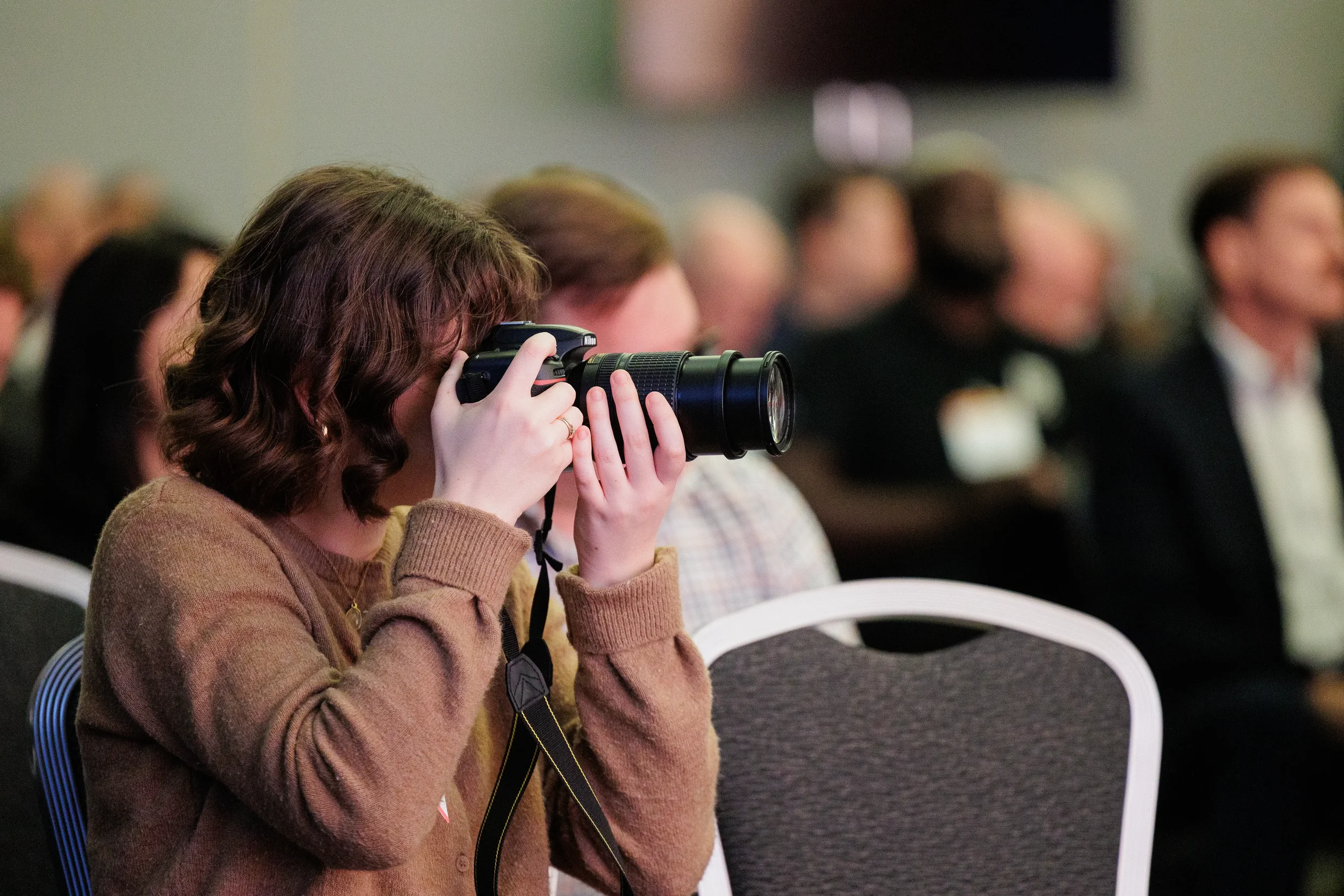 Photographer aims DSLR camera with telephoto lens during session at Chicago industry conference