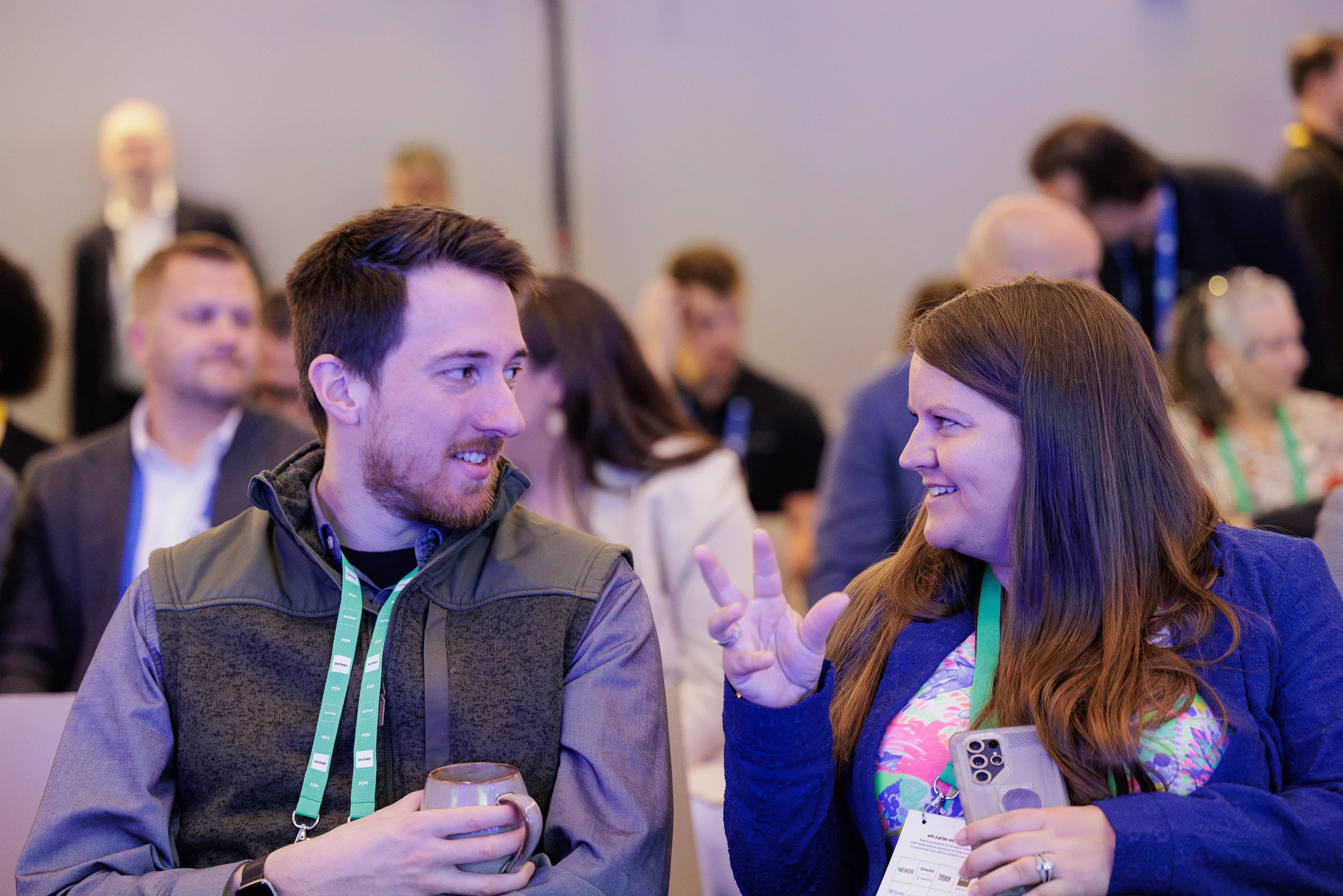 Two attendees chat while seated with green lanyards before session at Orlando industry conference
