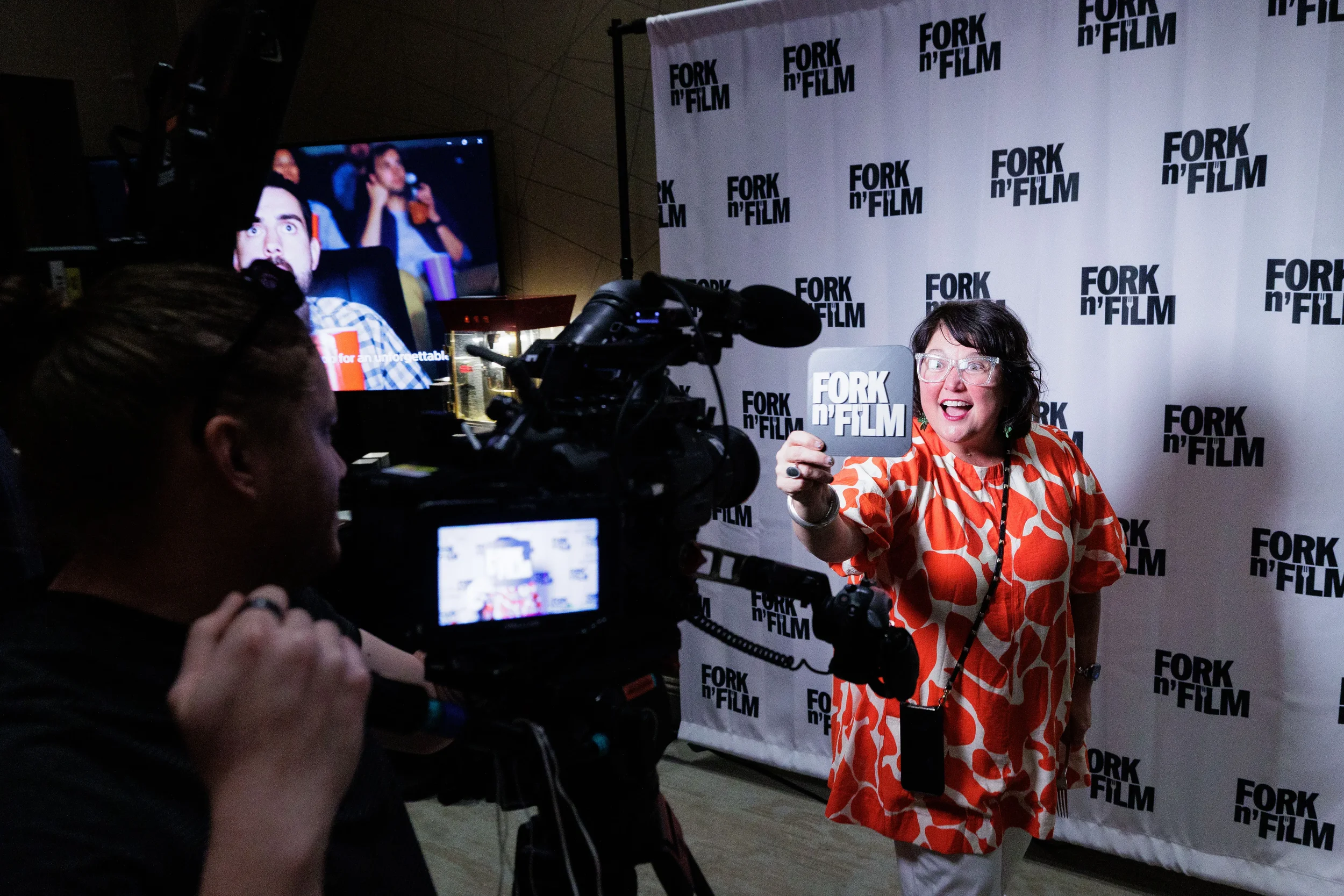 Smiling attendee poses with prop in front of sponsor step-and-repeat banner at Orlando corporate event