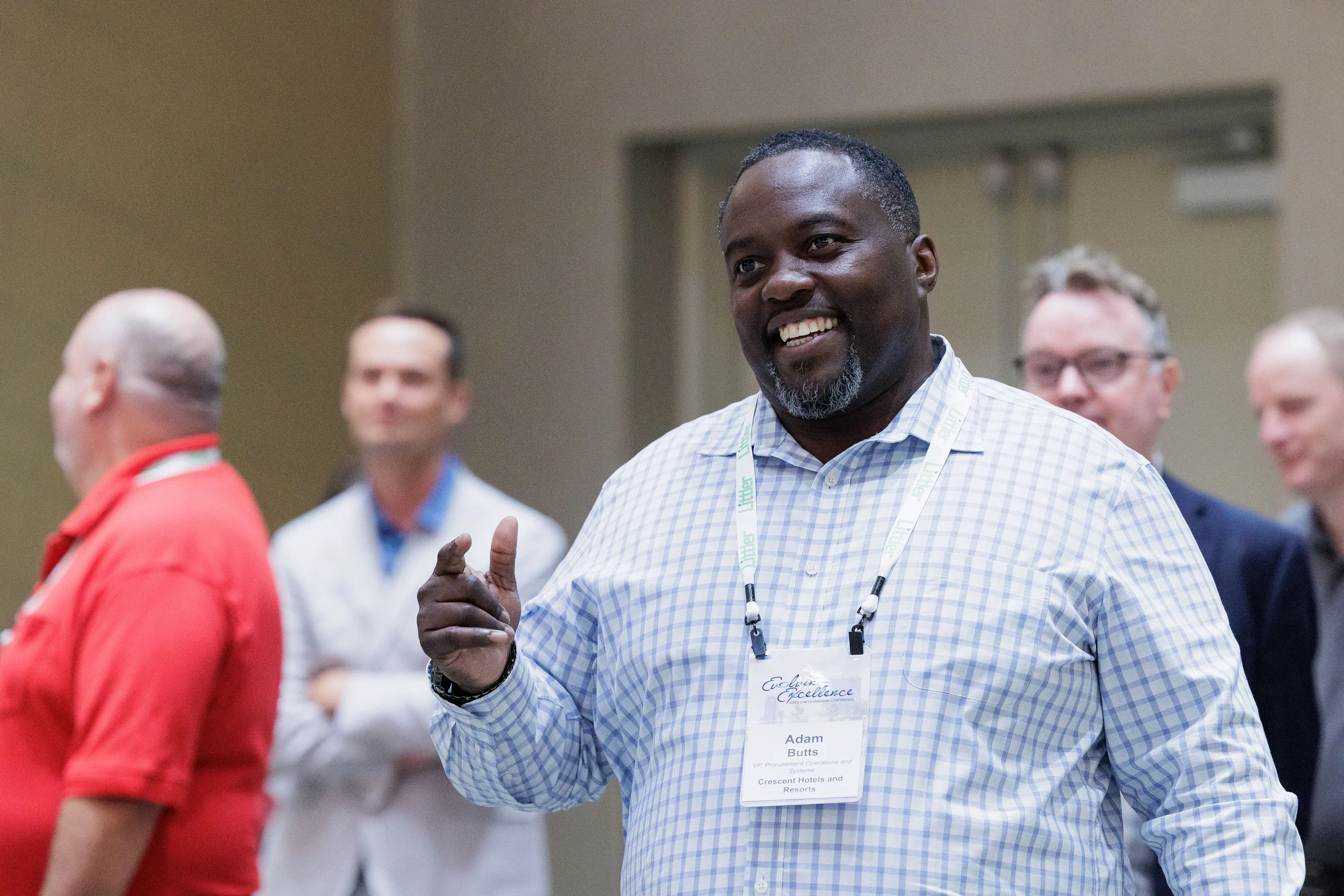 Smiling male attendee with lanyard gestures while networking at Chicago industry conference