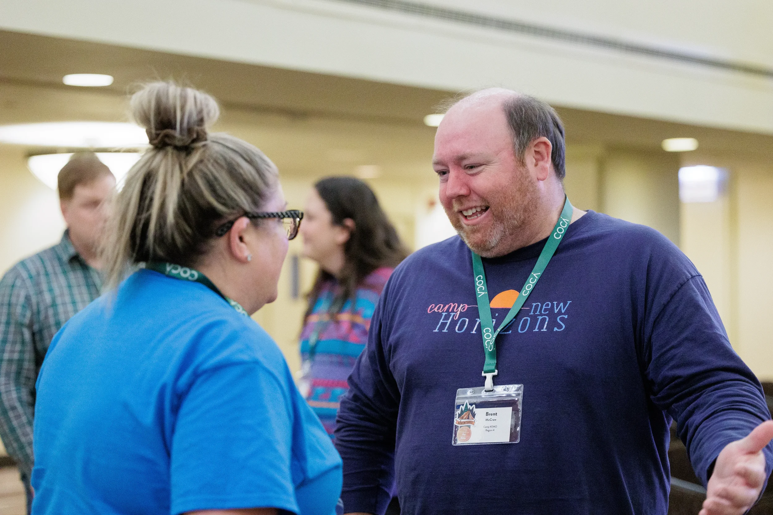 Two attendees share a laugh during networking break in hallway at Orlando conference