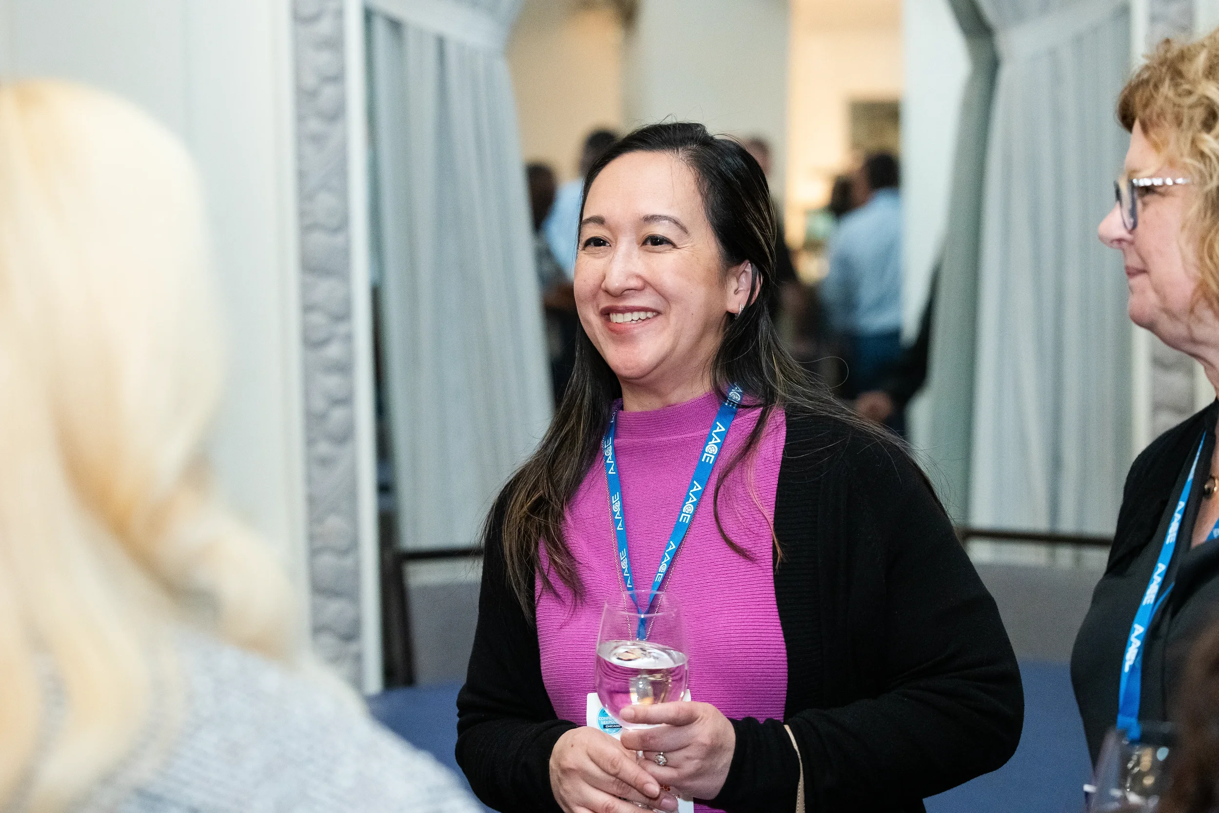 Attendee smiles while holding wine glass during reception at Chicago corporate conference event