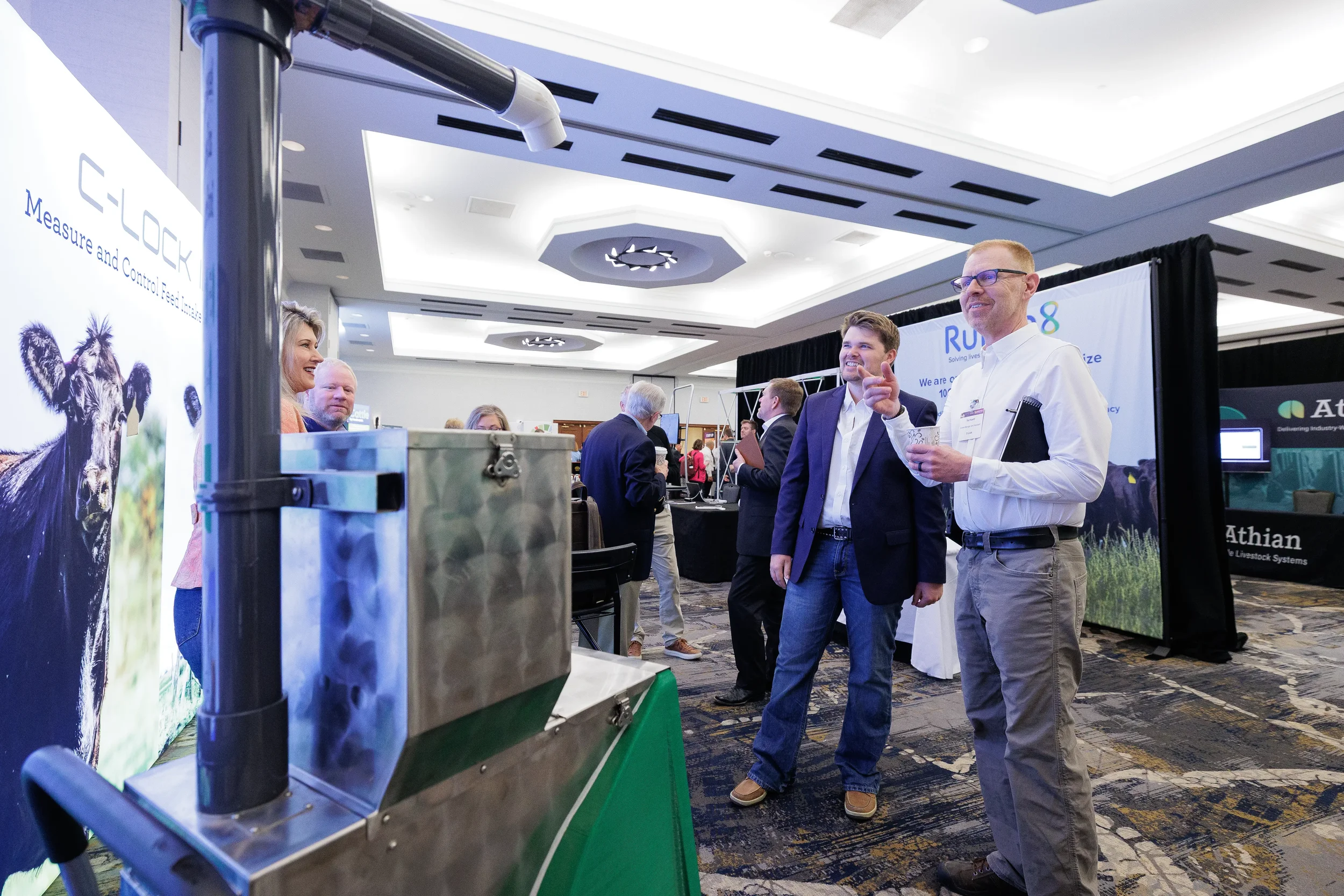 Attendees converse near exhibitor booth and equipment display at Orlando corporate conference