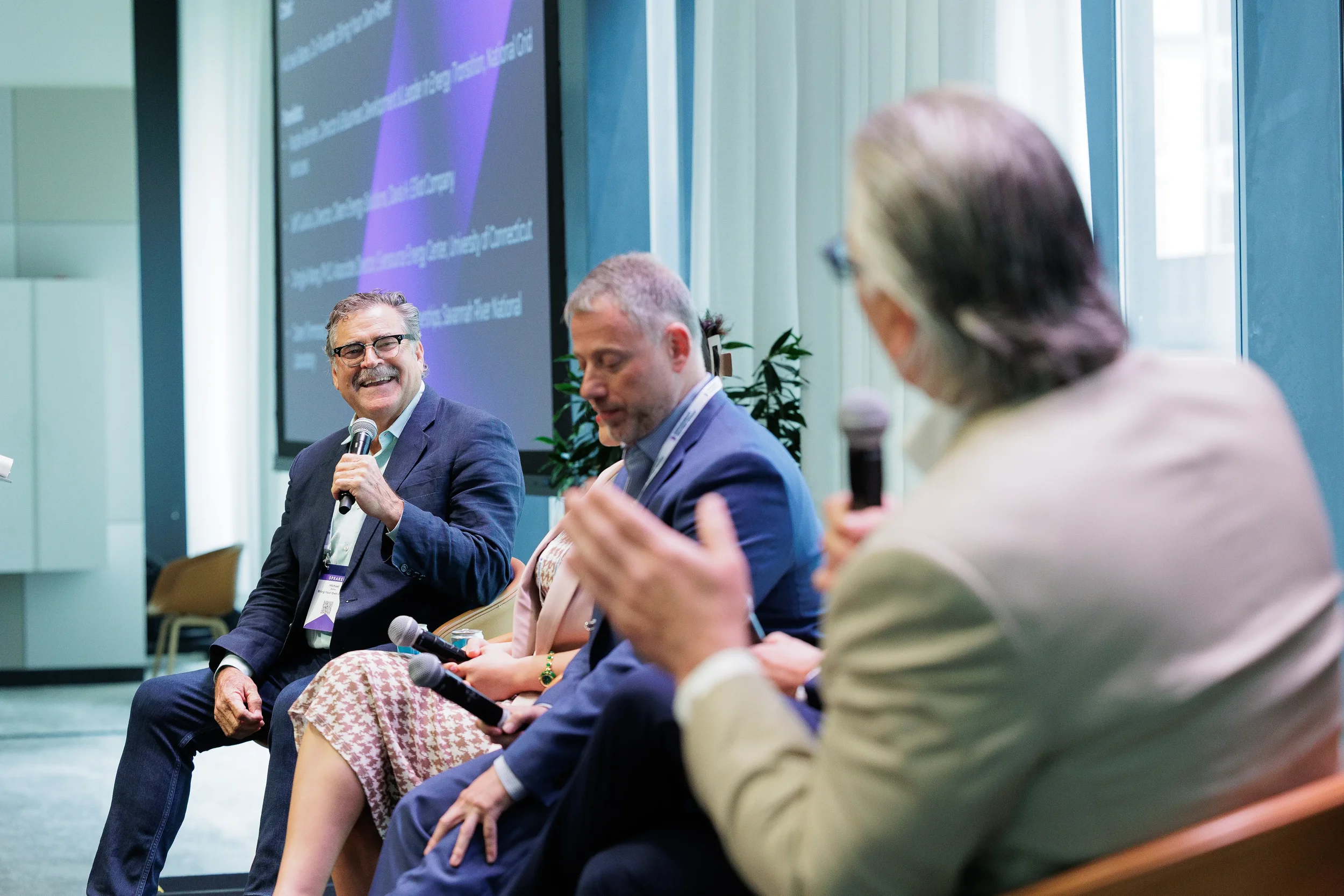 Panelists laugh while holding microphones during seated discussion at Orlando industry conference