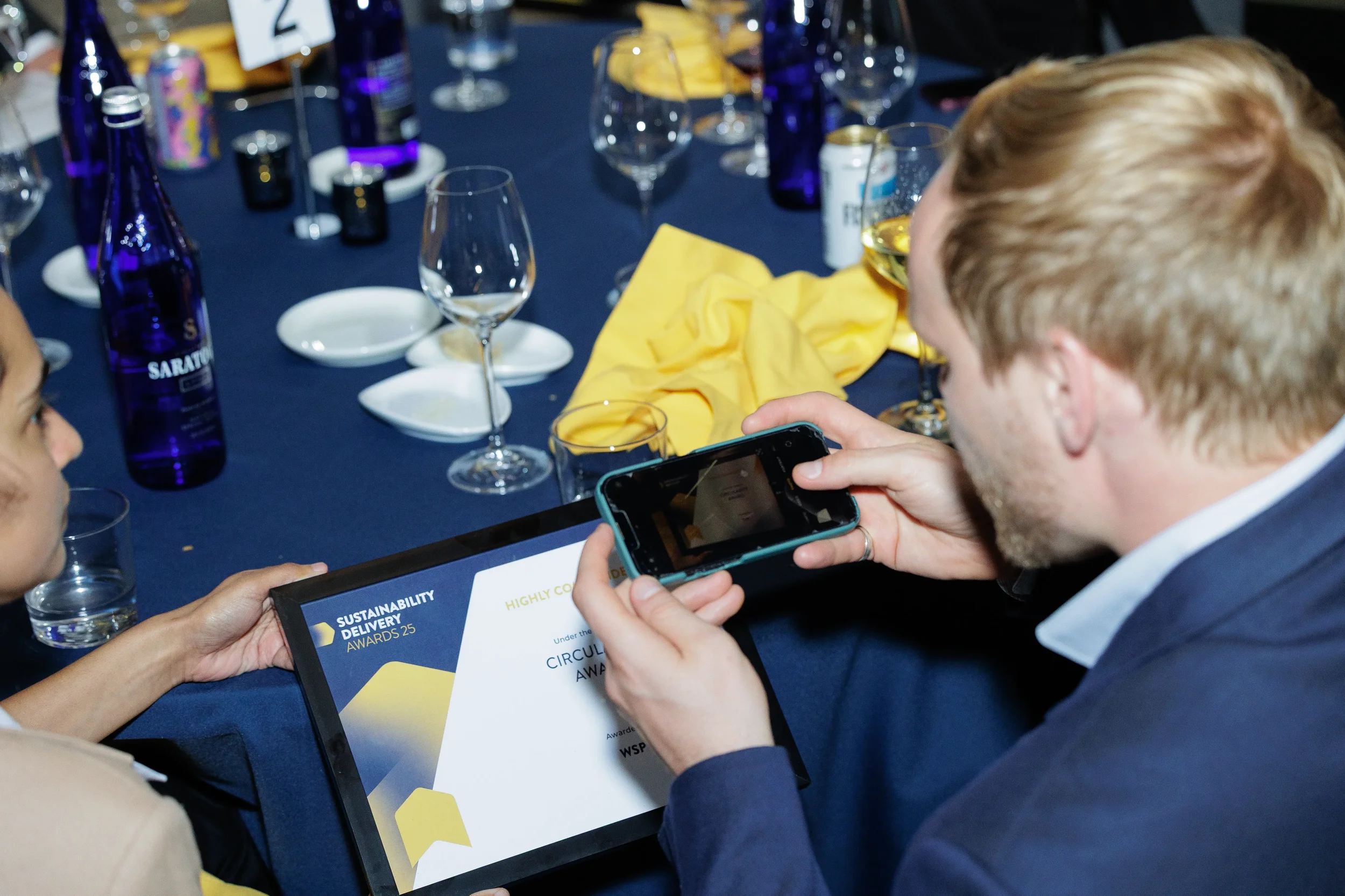 Attendees photograph award certificate at dinner table during Chicago corporate awards event