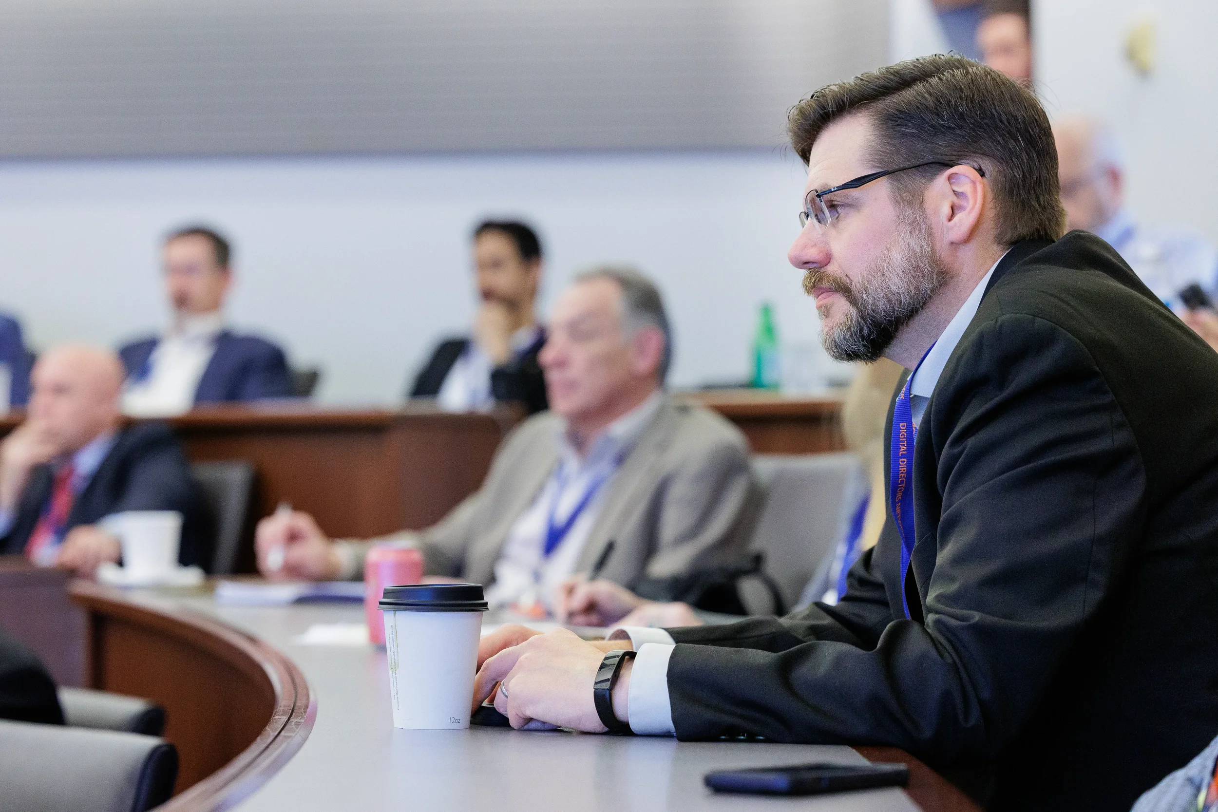 Male attendee with lanyard seated attentively in tiered room during Chicago corporate conference session