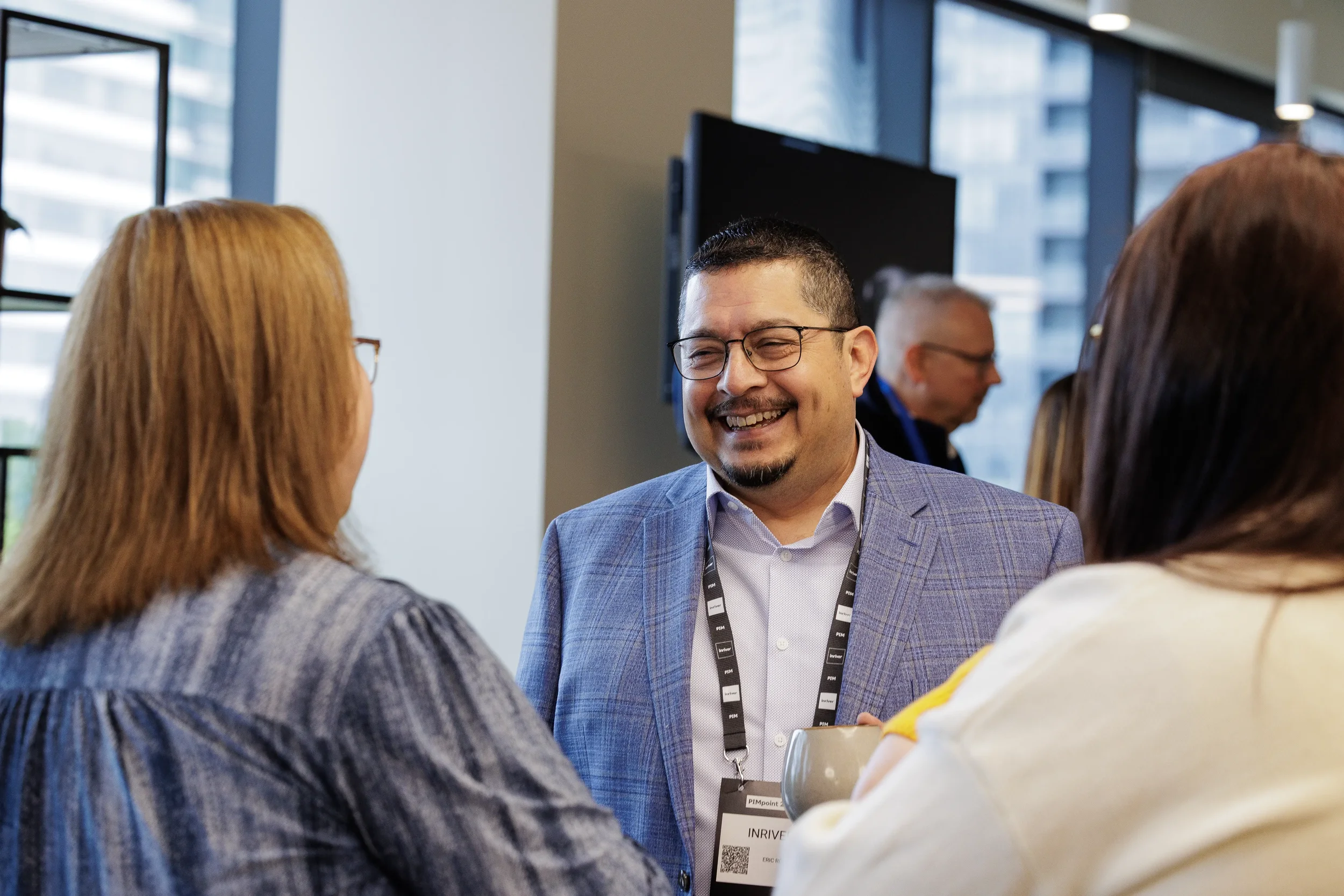 Smiling attendee in blue blazer laughs while networking with colleagues at Chicago corporate event