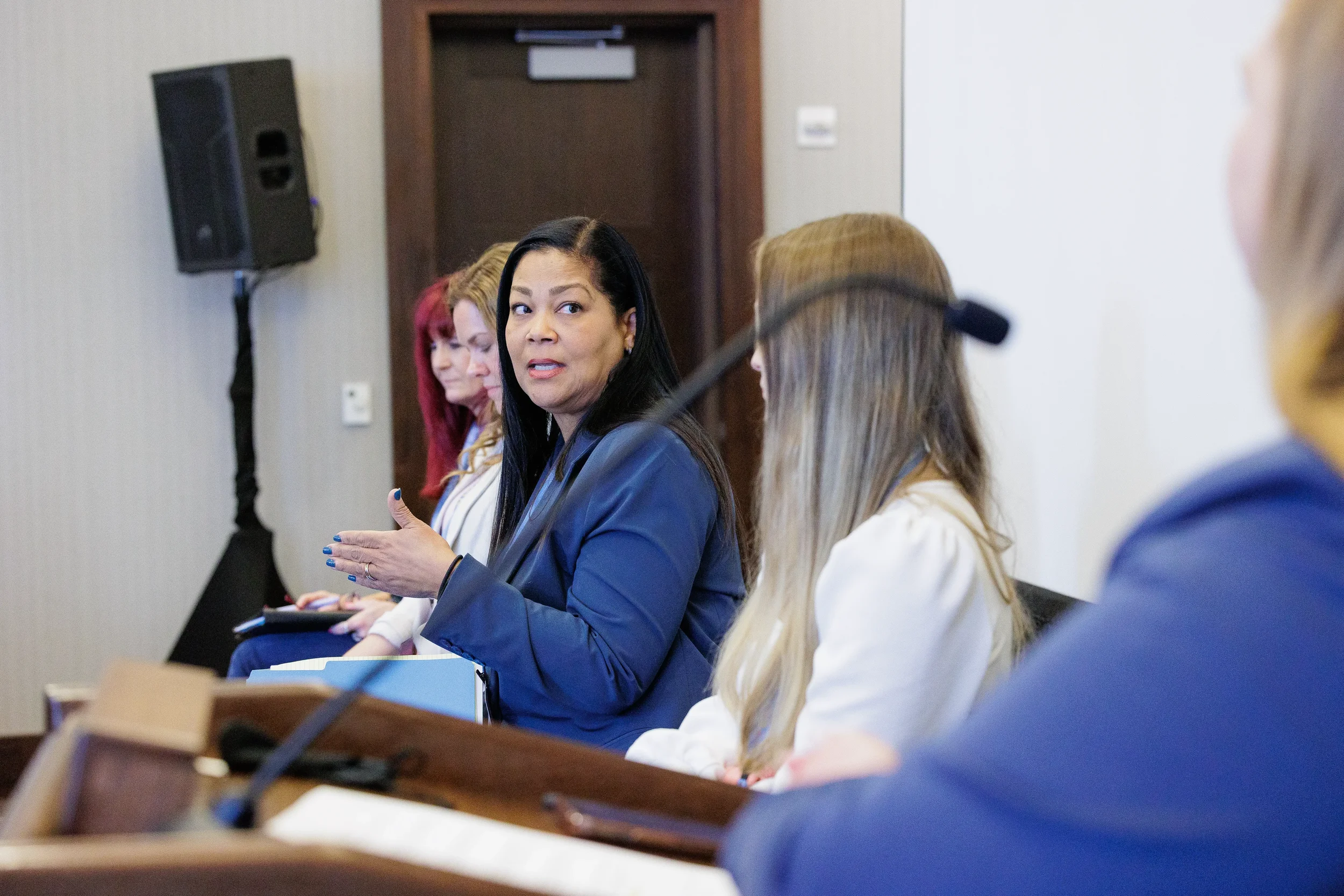 Panelist gestures while speaking alongside fellow panelists during breakout session at Orlando conference
