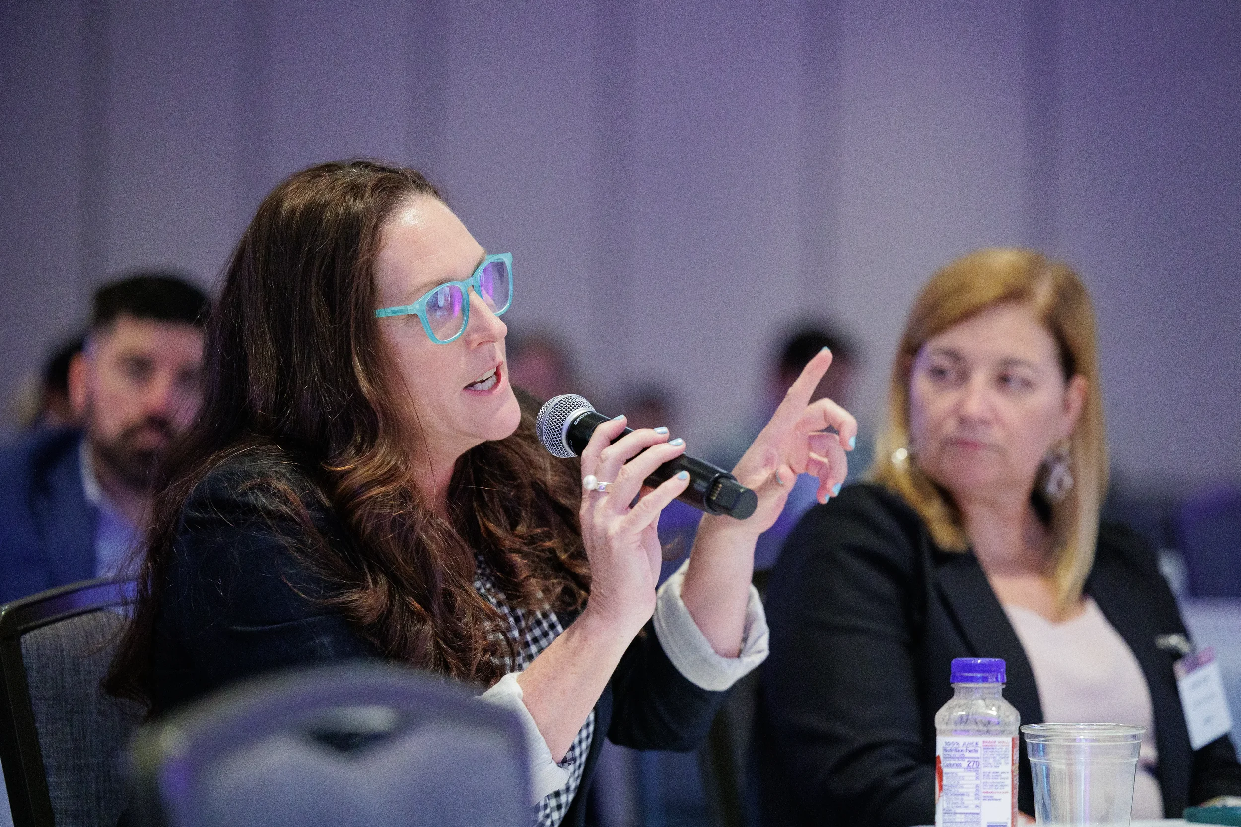 Attendee gestures while speaking into microphone during roundtable discussion at Chicago summit