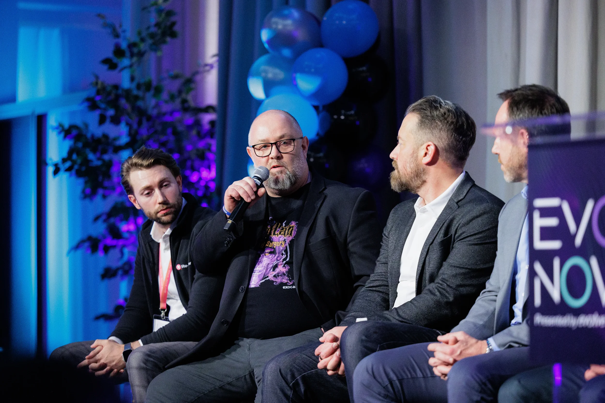 Panelist speaks into microphone while fellow panelists listen on stage at Chicago industry conference