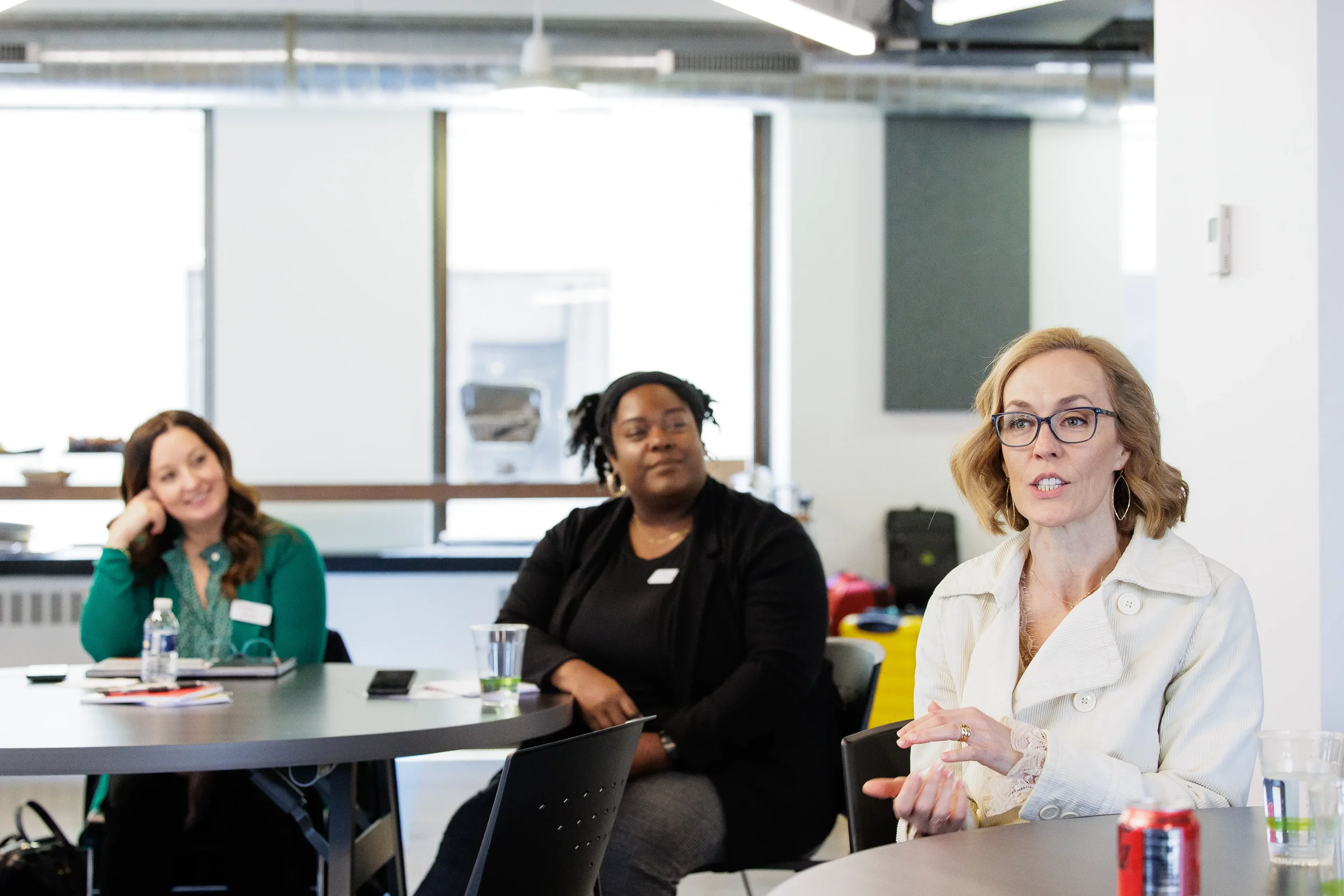 Three female attendees seated at tables listen and engage during a session at Chicago corporate event