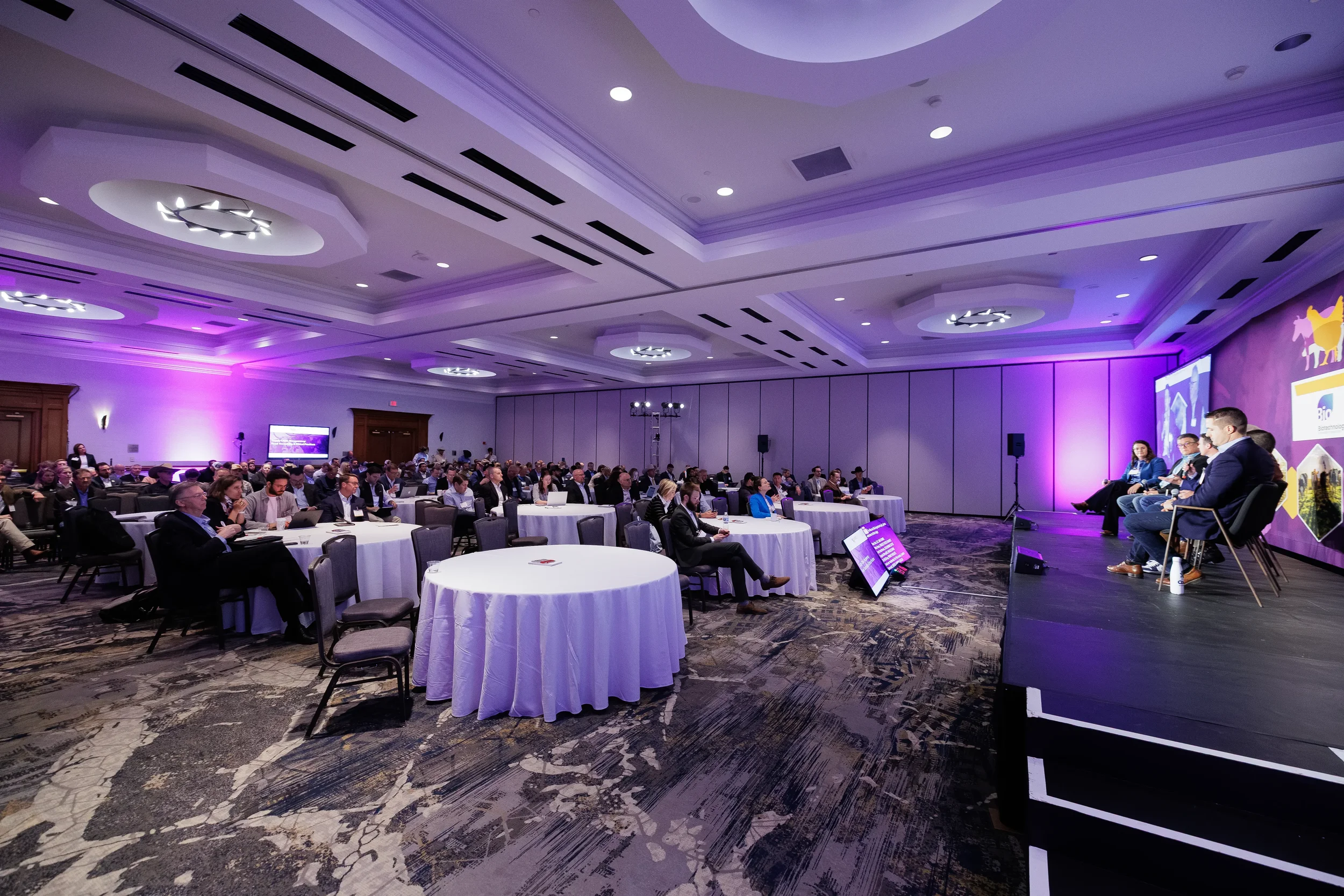 Wide view of ballroom audience and panel discussion on stage at Chicago corporate summit
