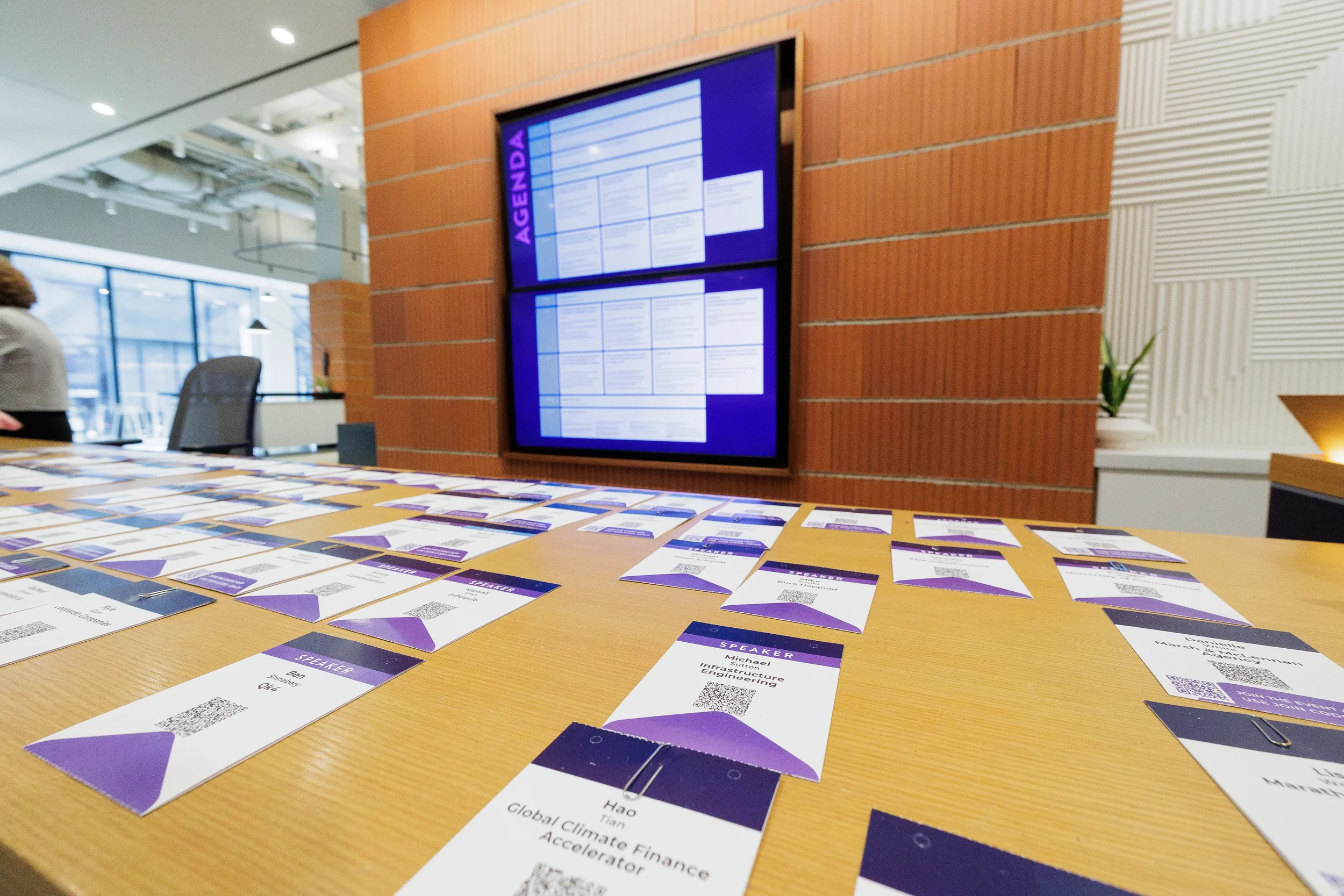 Speaker badges laid out on table with agenda screen at Orlando industry conference