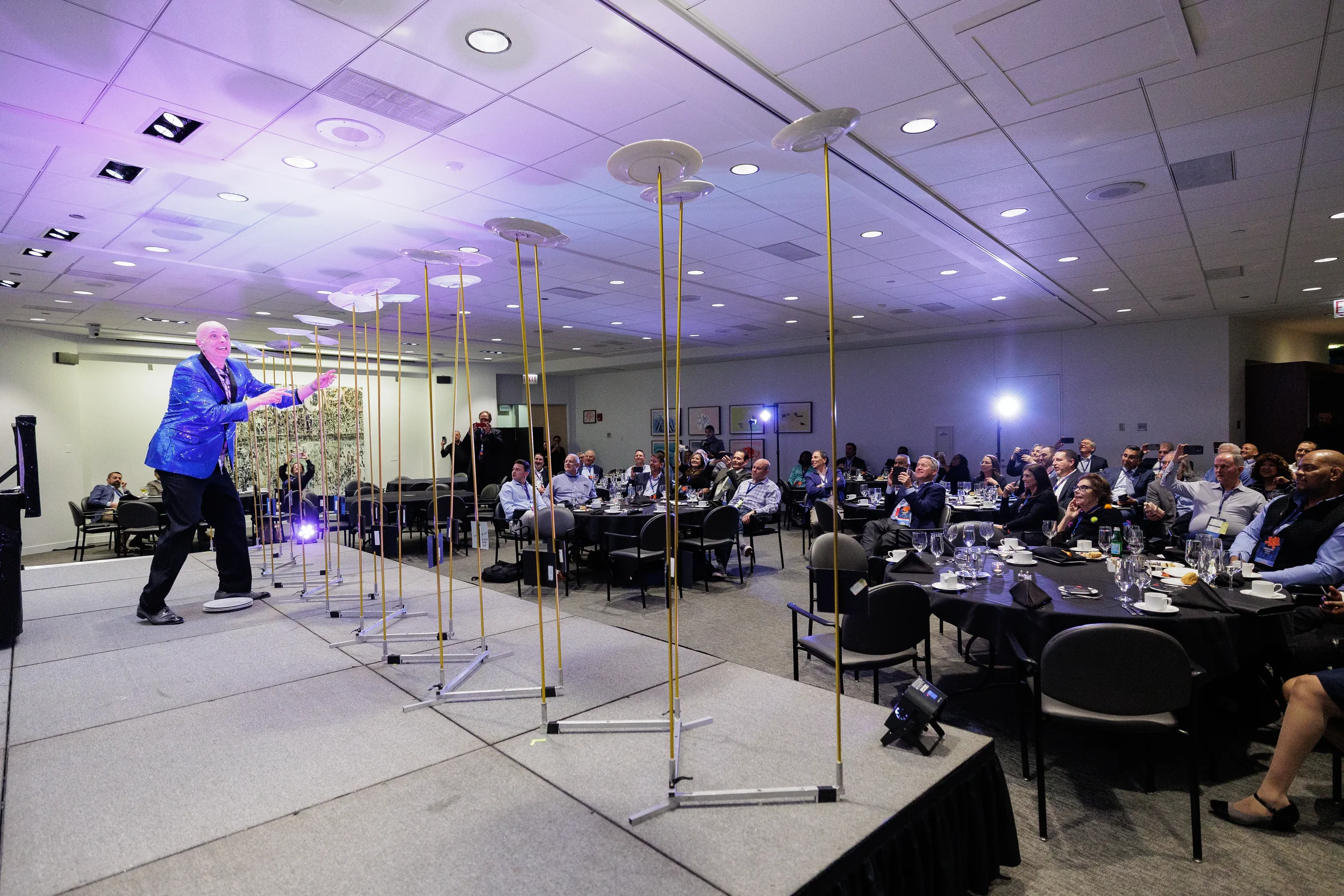 Plate-spinning entertainer performs on stage before applauding audience at Chicago corporate conference event