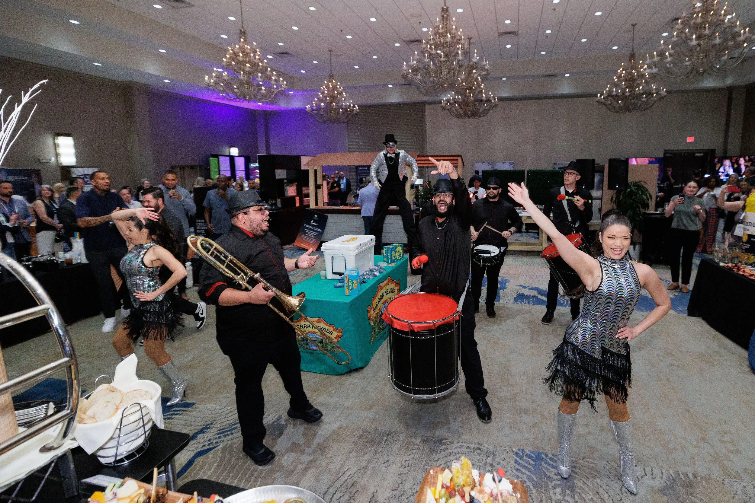 Live band with trombone, drummers, and fringe dancers perform under chandeliers at Chicago corporate event