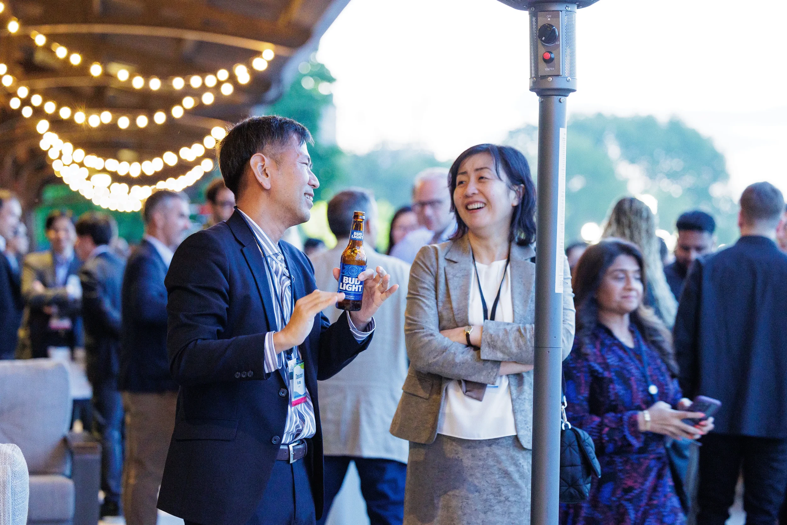 Attendees laugh together under string lights during Chicago evening reception