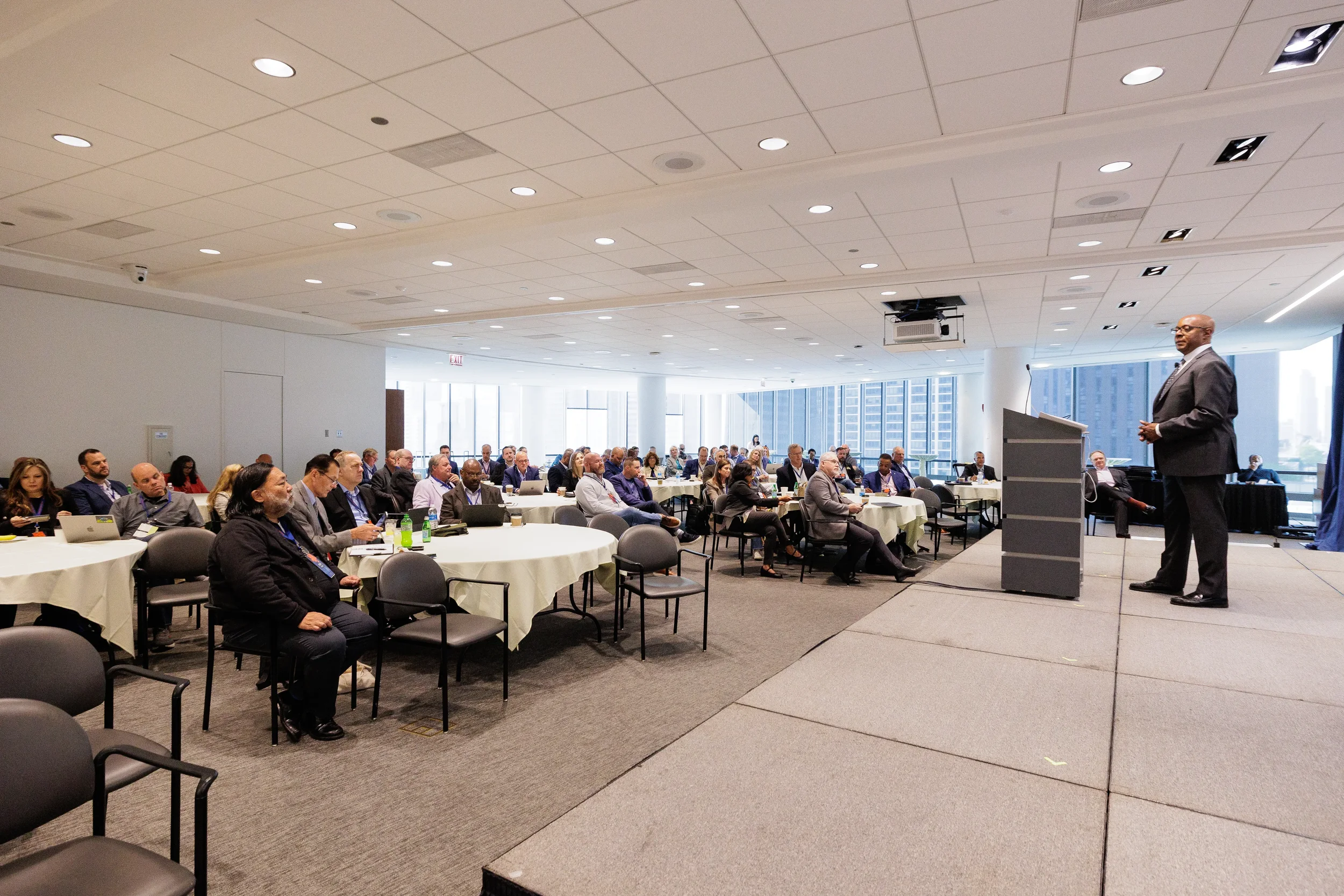 Male speaker stands at podium on stage addressing full room of attendees at Chicago corporate event