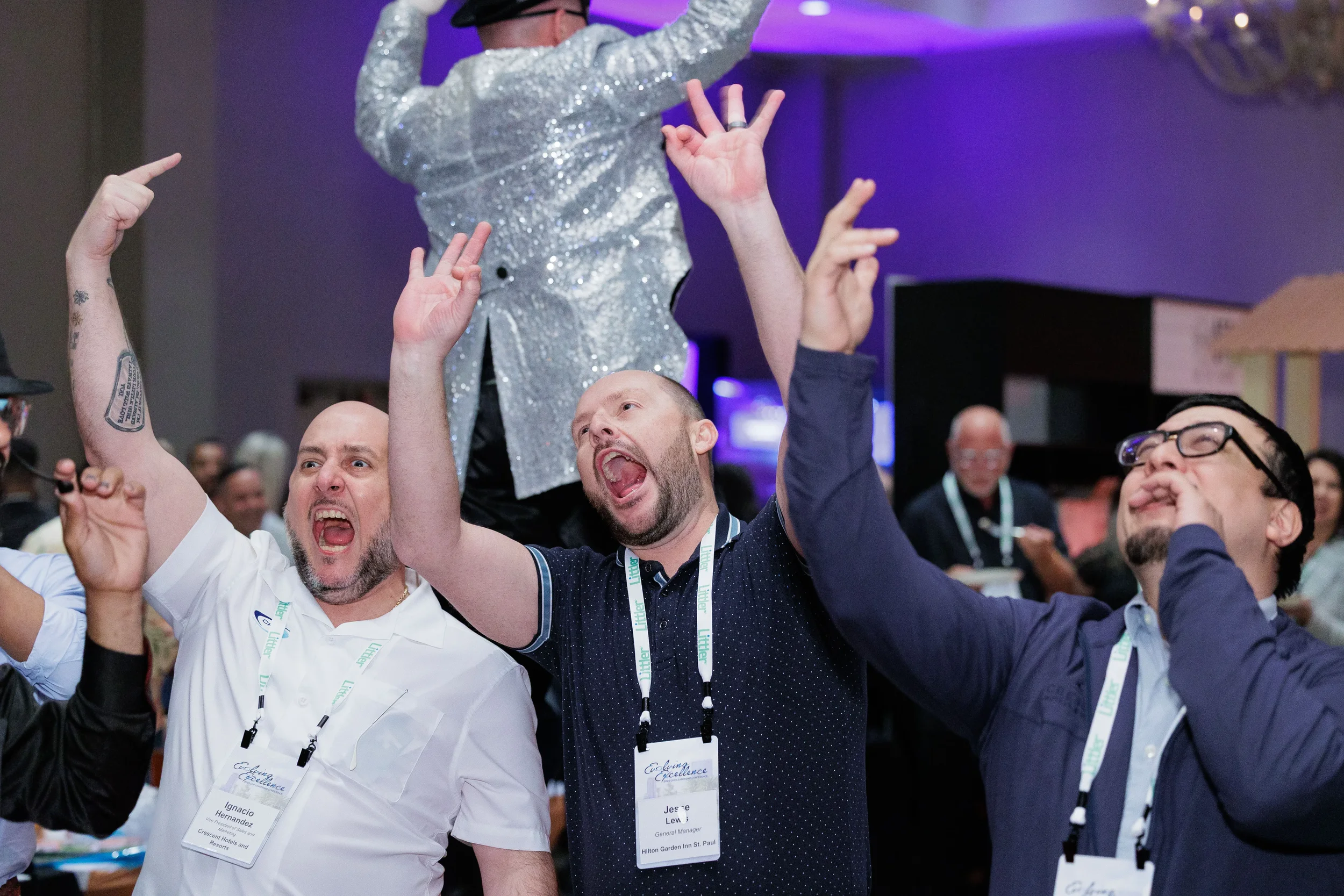 Three attendees cheer with hands raised near sequin stilt performer at Chicago corporate conference reception