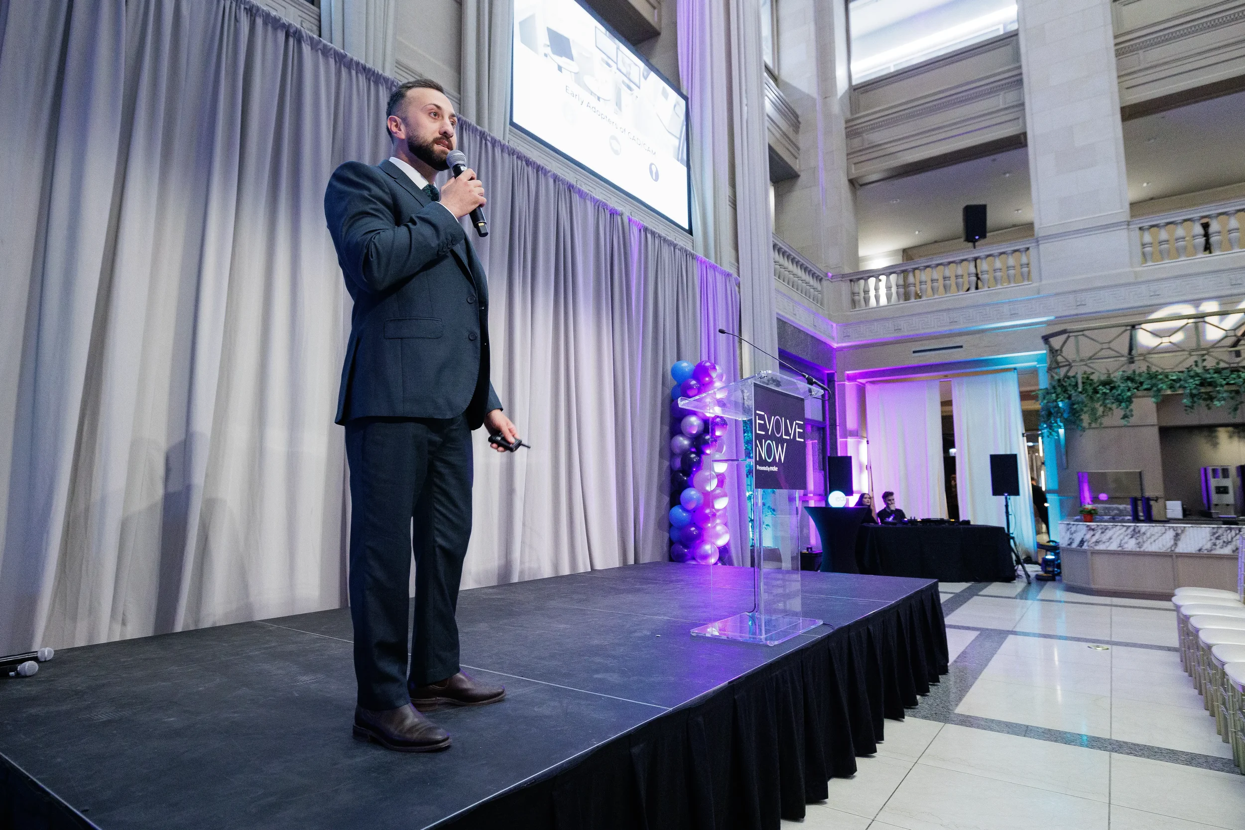 Speaker presents on stage with projection screen in grand ballroom at Orlando corporate event