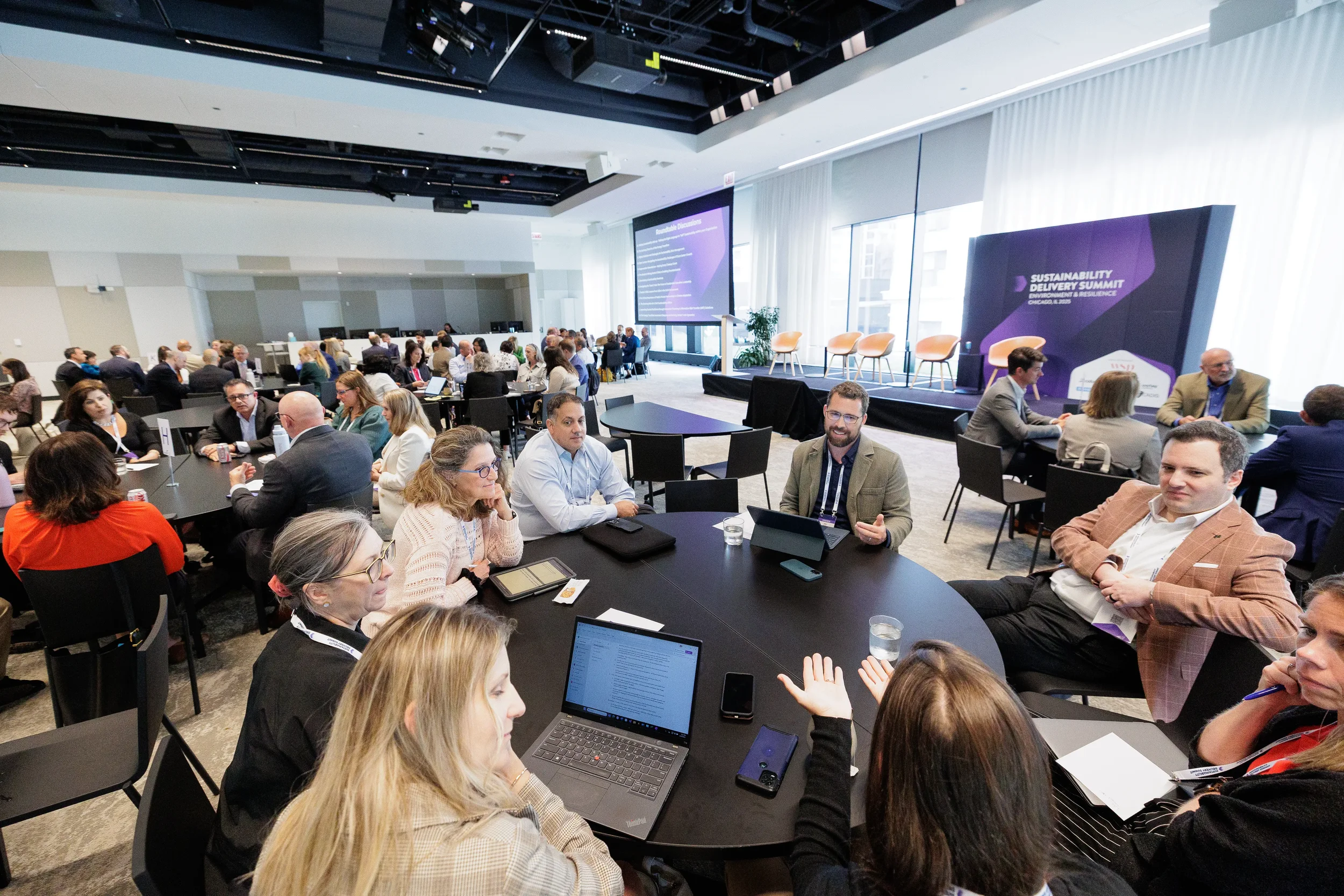 Attendees engage in roundtable discussion with laptops during Chicago industry conference session