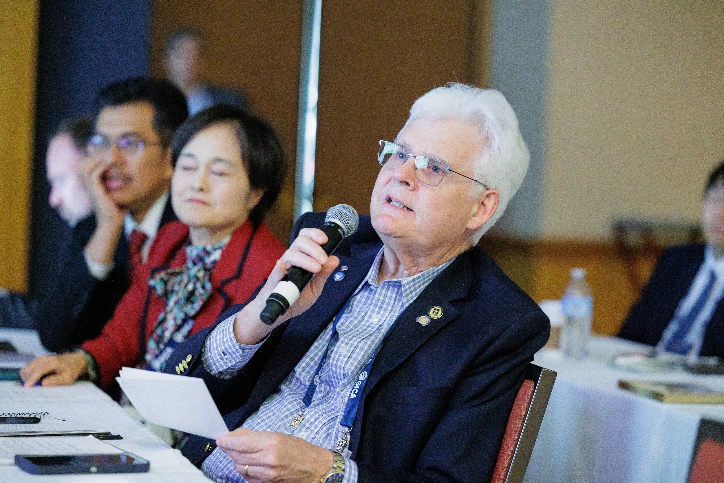 Older Caucasian man speaks into a microphone while at a table during an Orlando conference