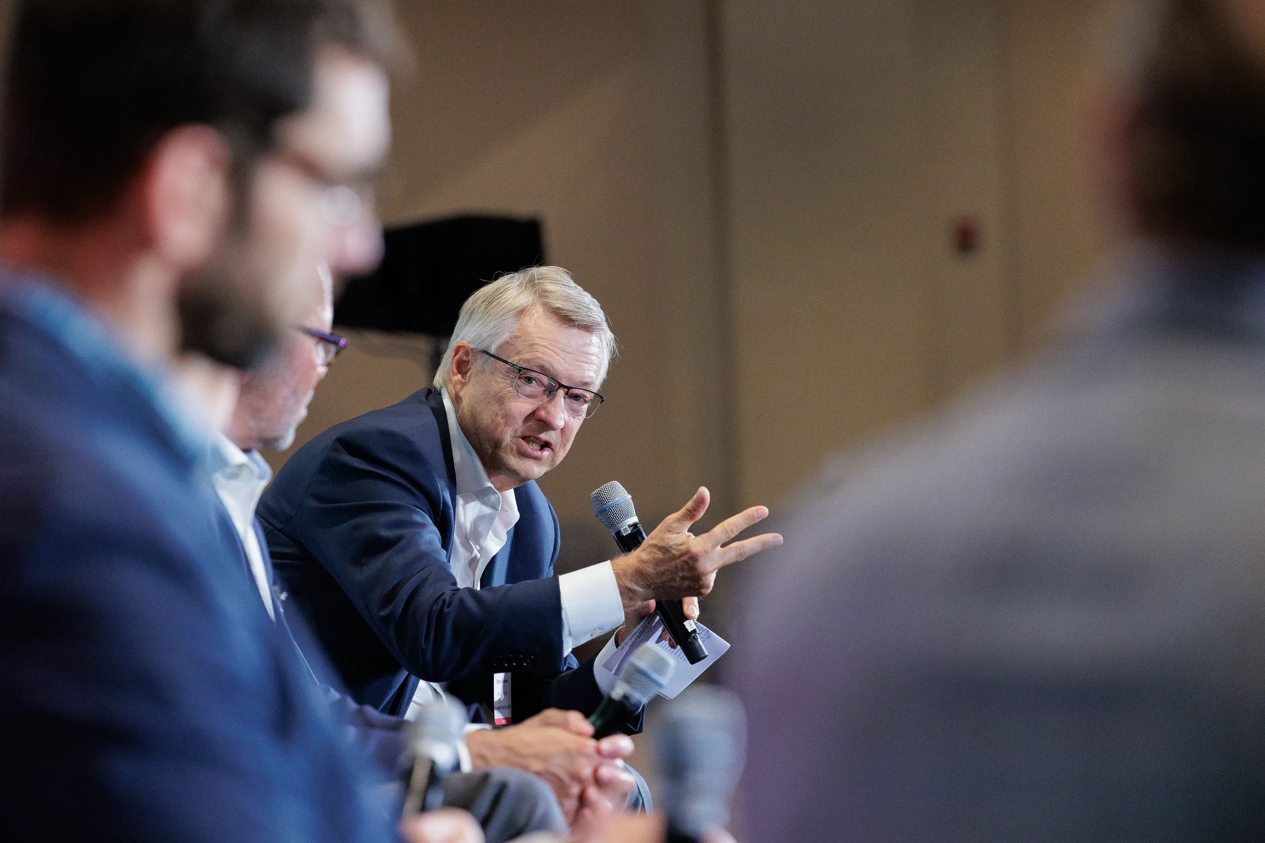 Panelist gestures expressively while speaking into microphone during discussion at Orlando industry conference