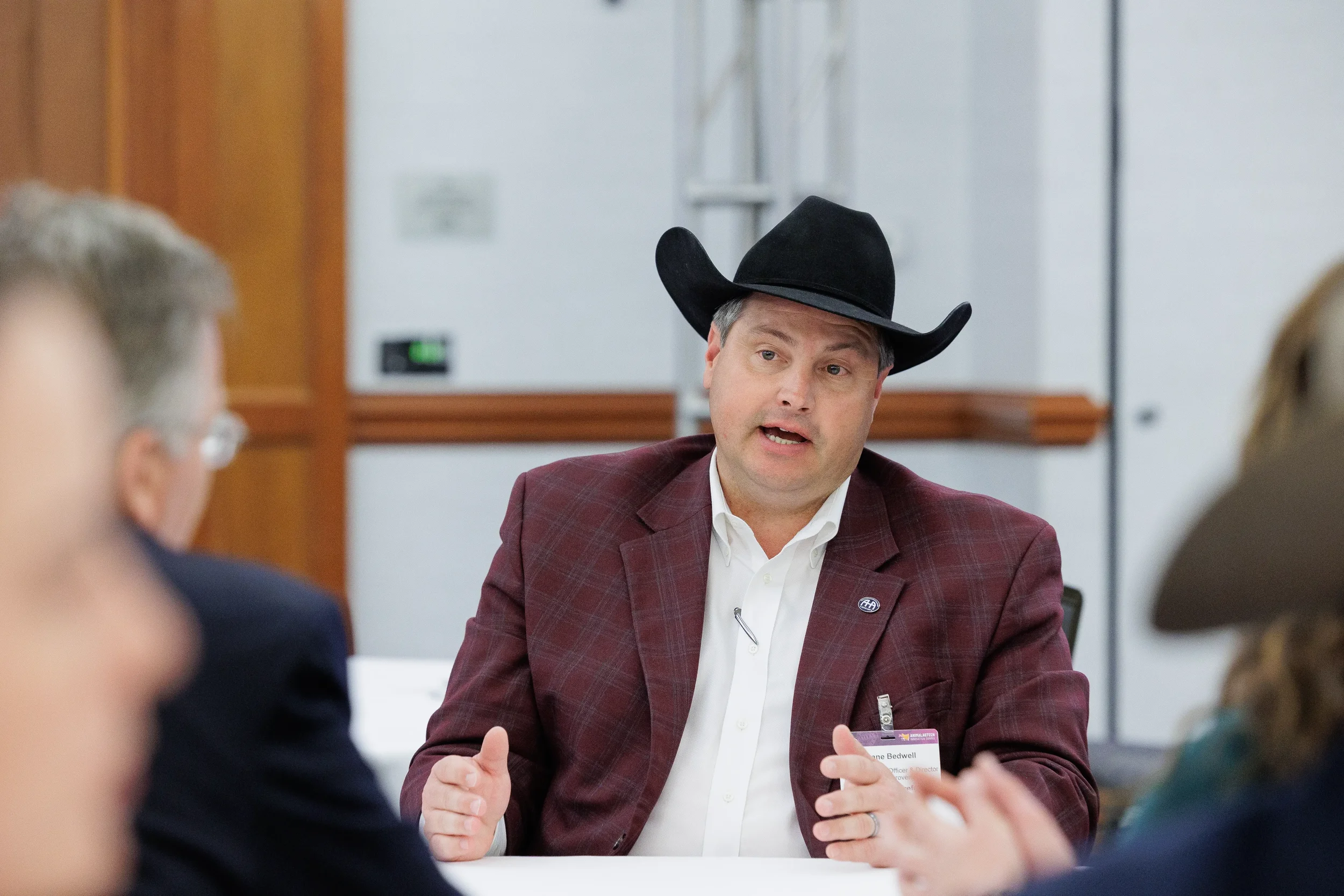 Attendee in cowboy hat gestures while speaking at roundtable during Orlando corporate conference