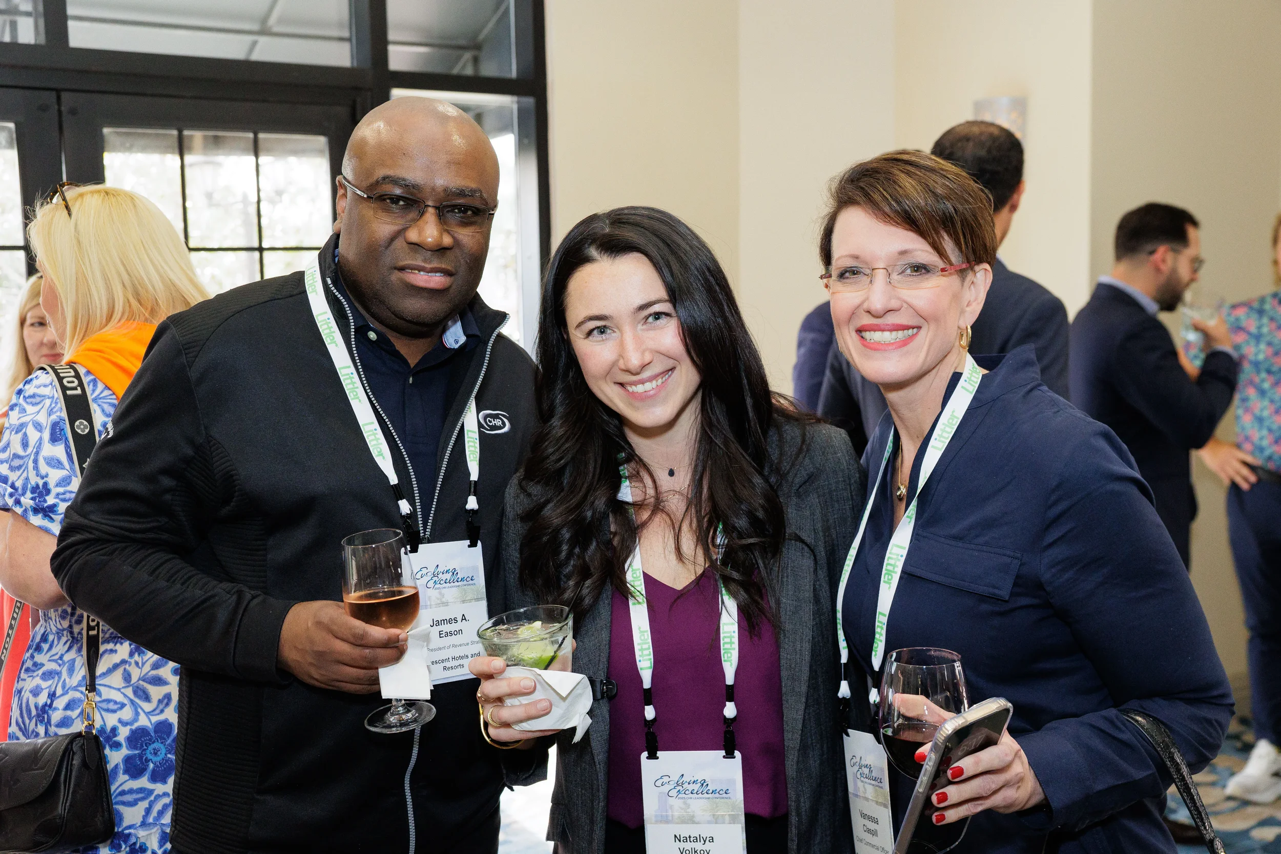 Three attendees with lanyards smile and mingle over drinks at Chicago corporate conference networking reception