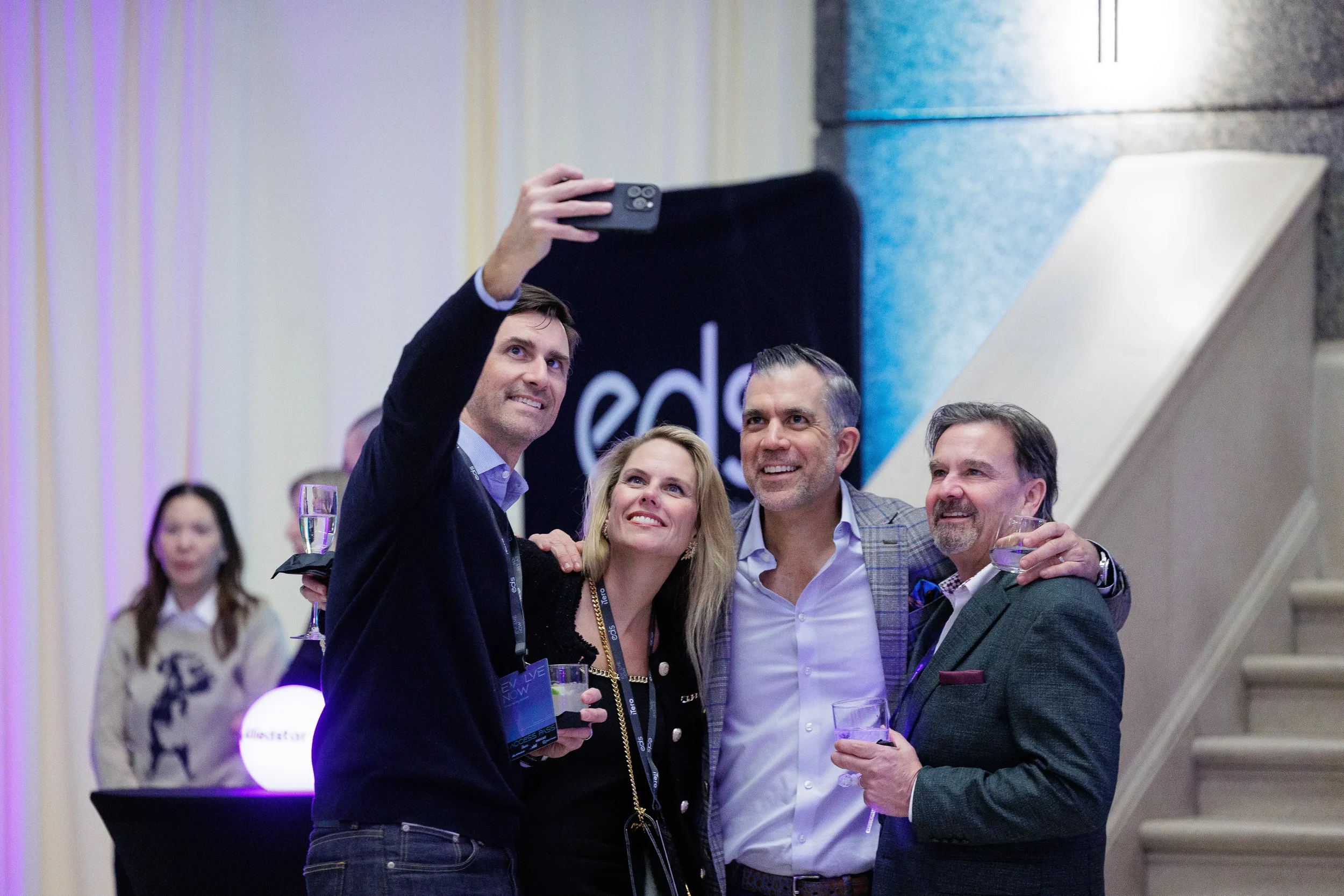 Four attendees take a group selfie with drinks during networking reception at Orlando corporate event