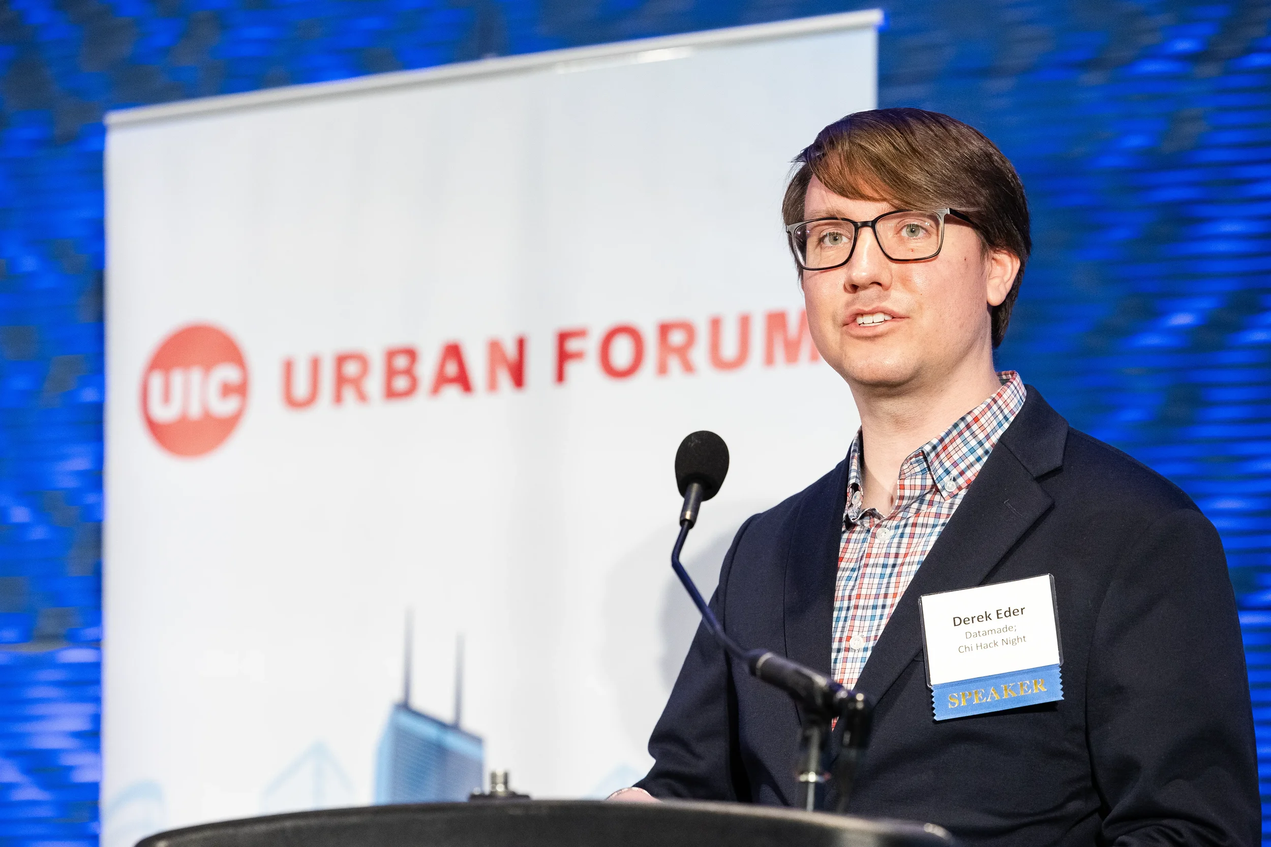 Speaker addresses audience from podium beside event banner at Chicago industry conference