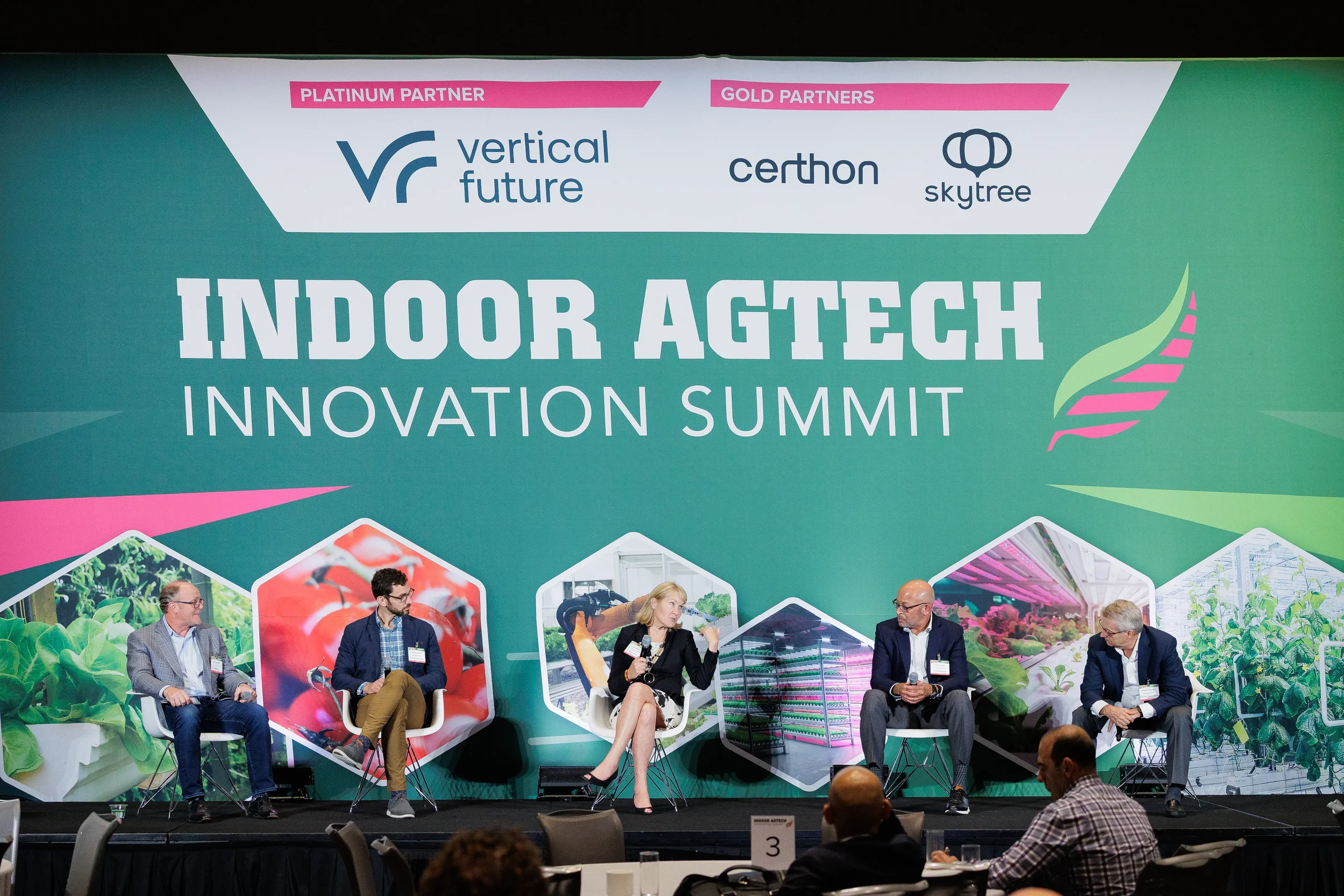 Five panelists seated on stage in front of large branded backdrop at Chicago industry conference