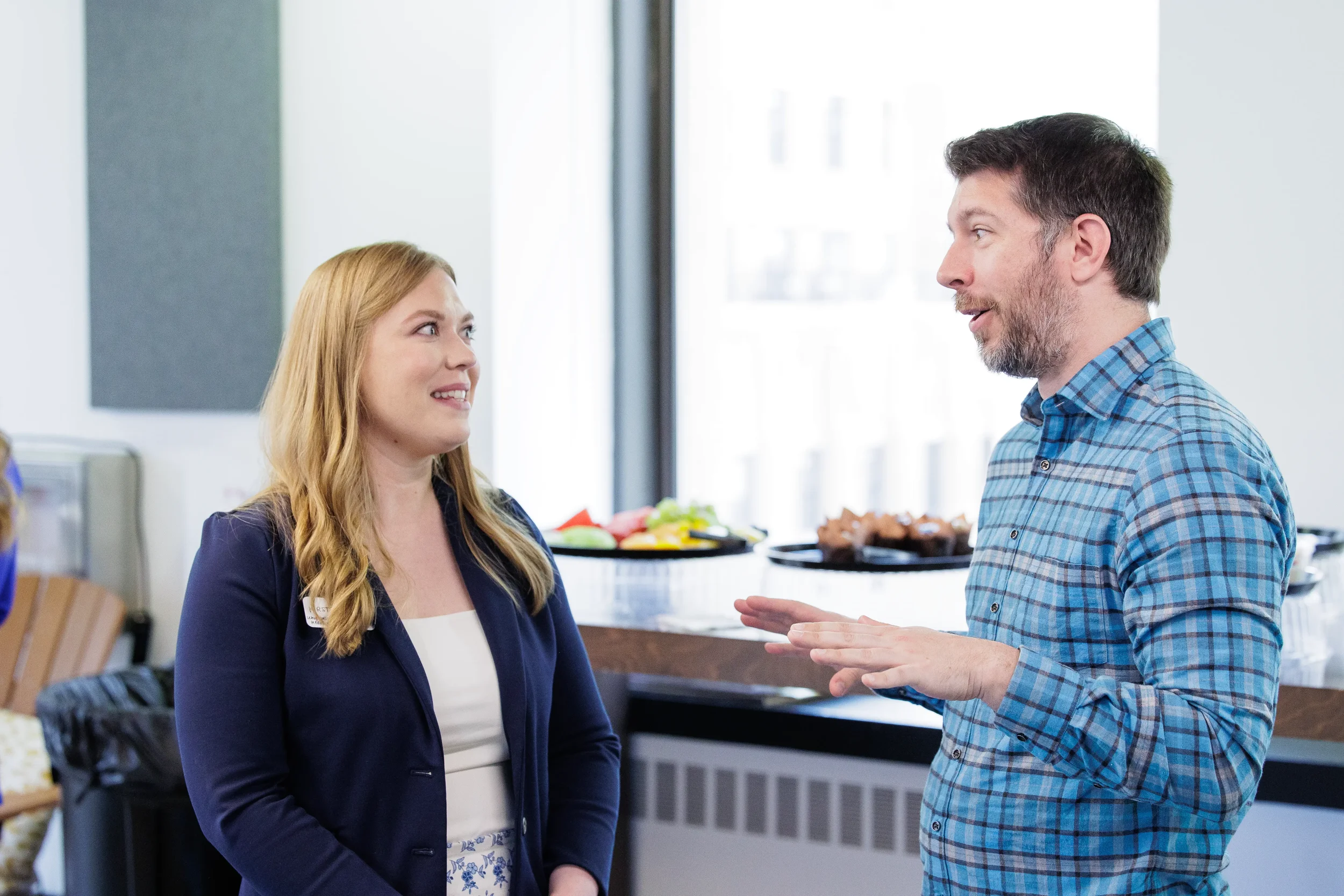 Two attendees face each other in conversation near a food table during Orlando industry conference