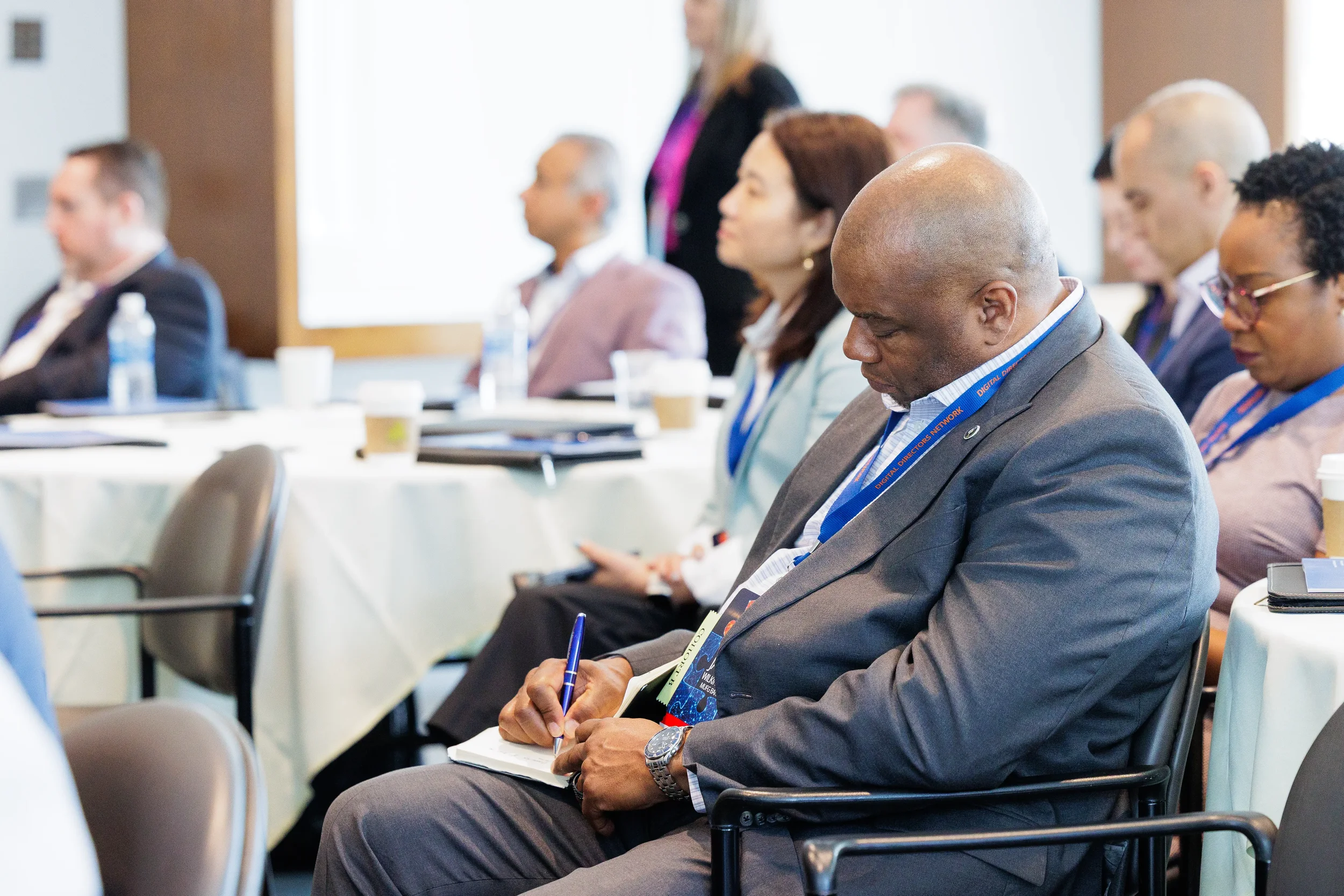 Male attendee with lanyard takes notes in notebook while seated at Orlando industry conference session