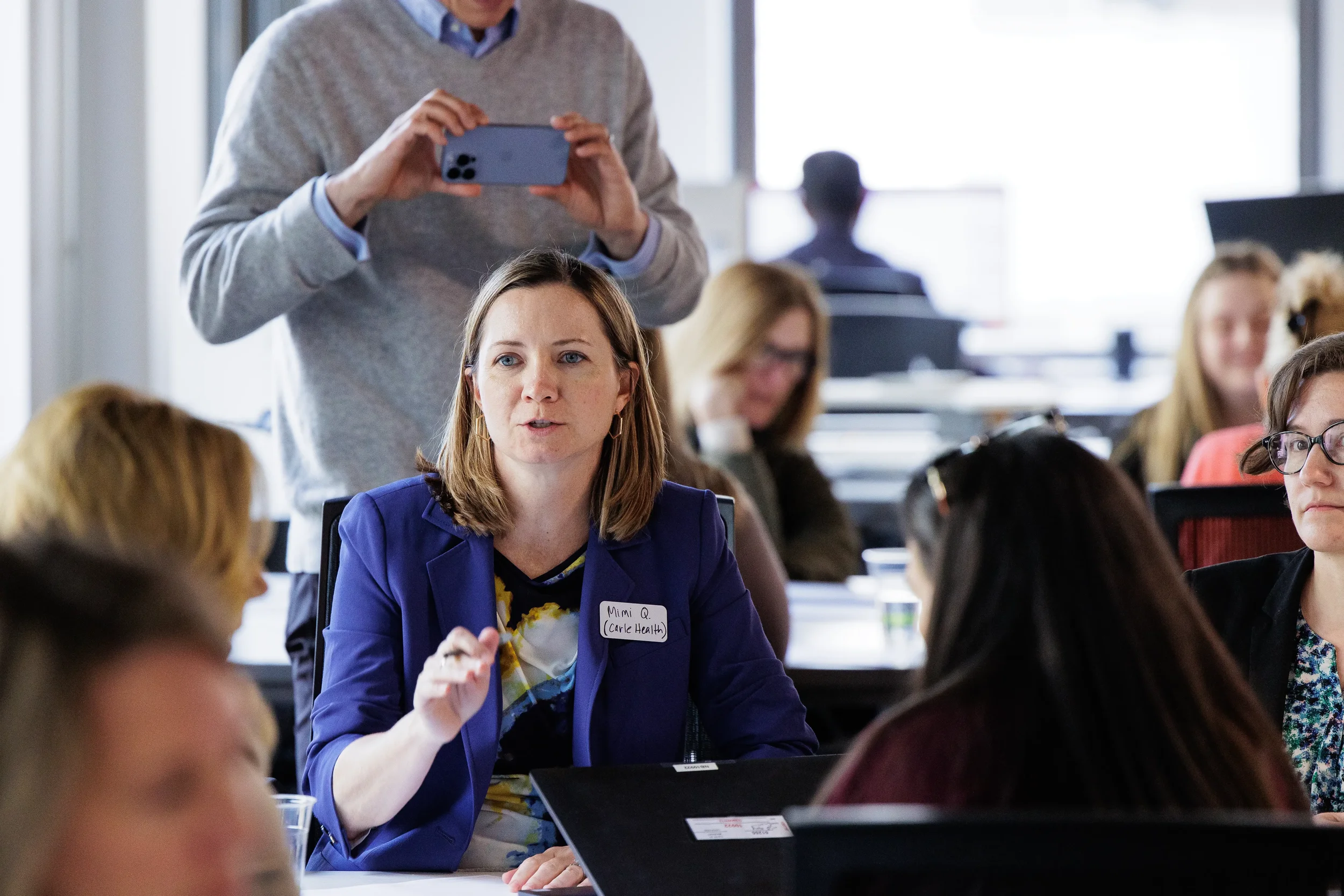 Female attendee gestures while speaking at a table surrounded by others at Chicago industry conference