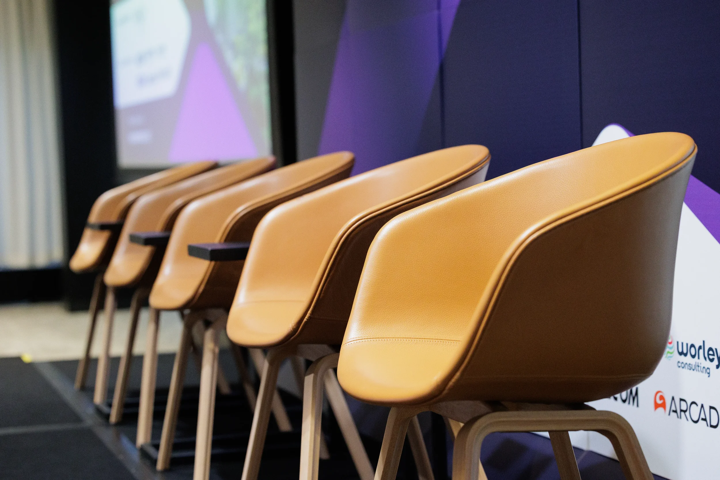 Row of leather panel chairs lined up on stage with sponsor branding at Orlando industry conference