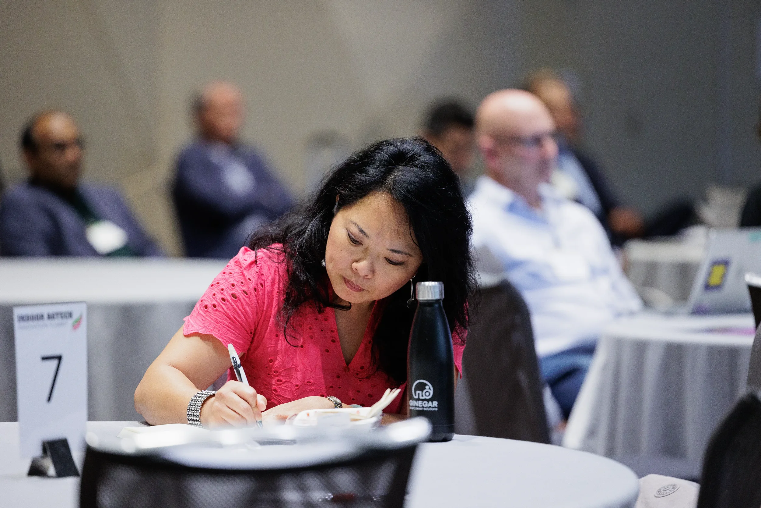 Attendee writes notes at numbered round table during session at Orlando industry conference event