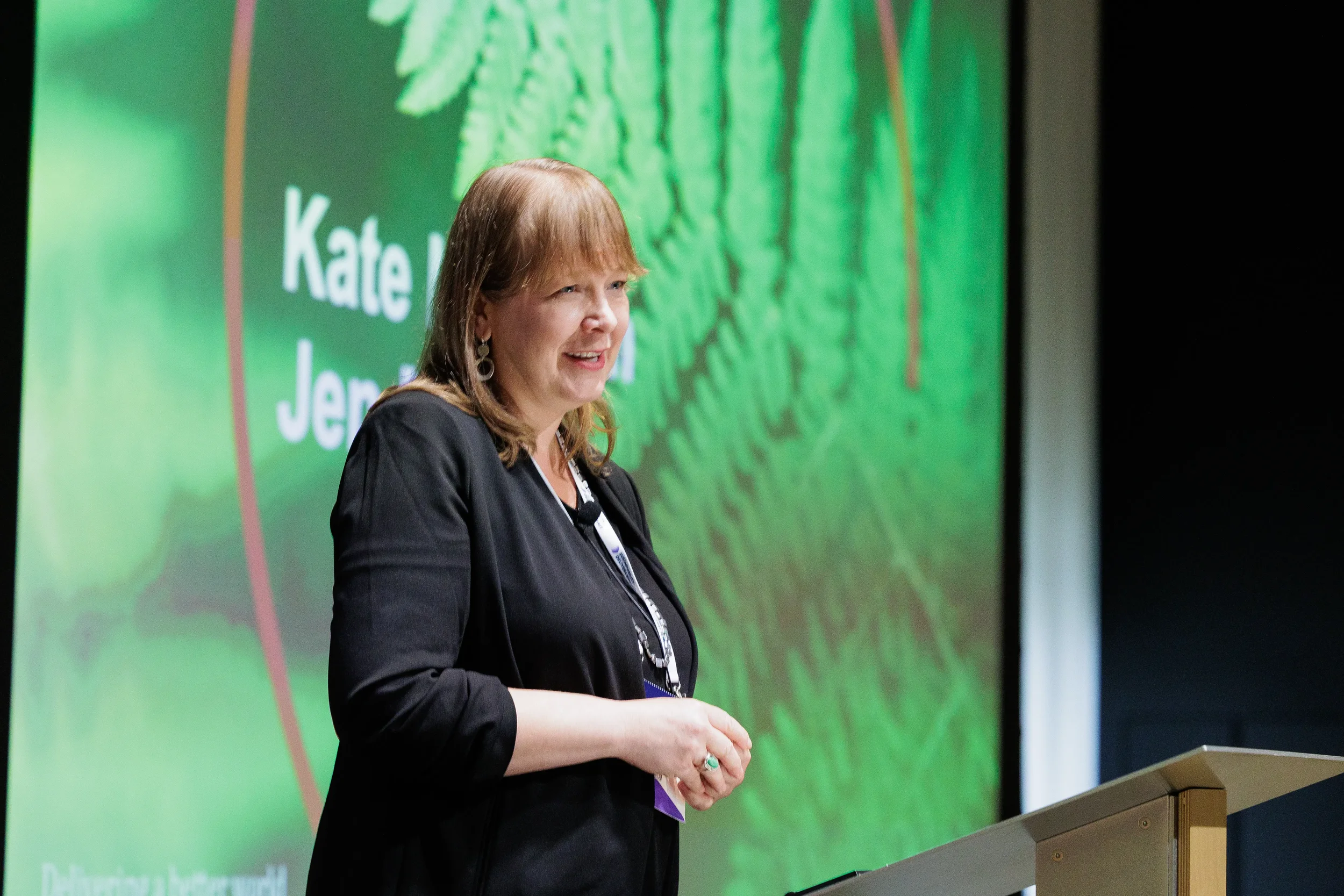Speaker presents from podium in front of presentation screen at Orlando industry summit