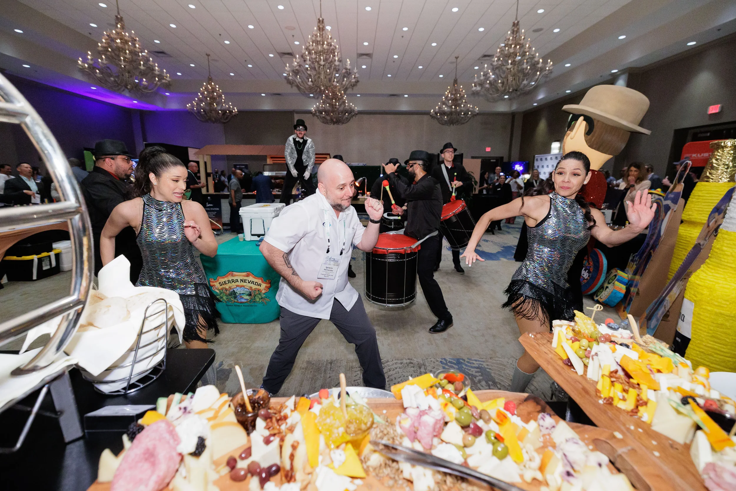 Attendee dances between two sequin performers near charcuterie board at Orlando corporate conference ballroom