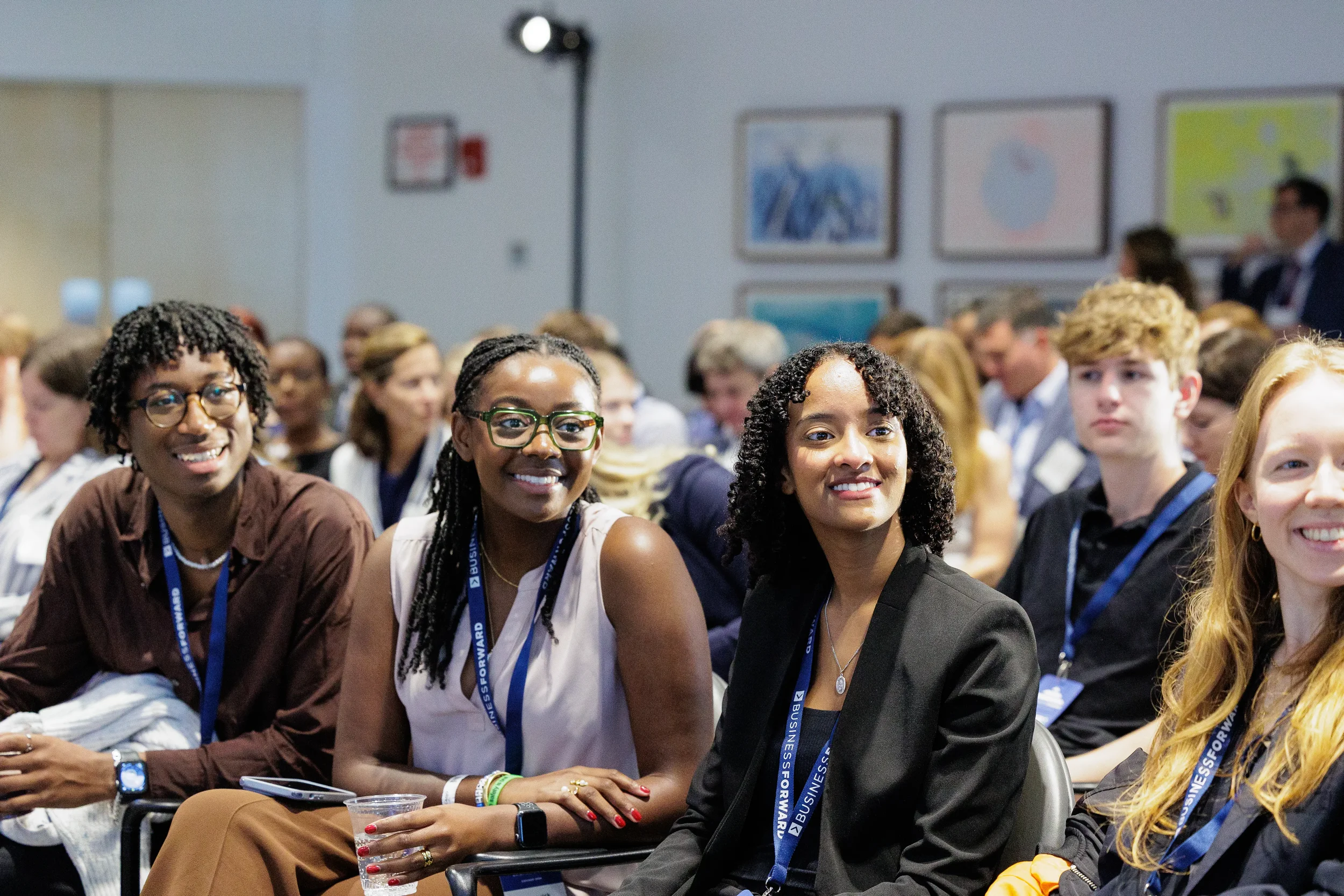 Smiling attendees wearing conference lanyards seated together in packed audience at Chicago corporate event