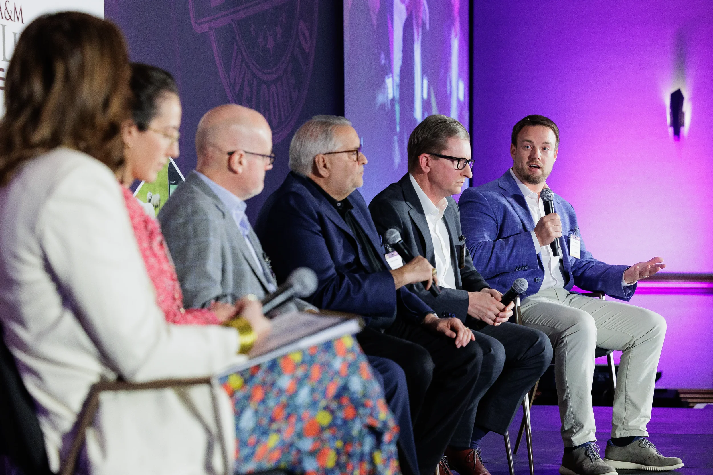Six panelists discuss on stage with purple lighting at Chicago industry conference