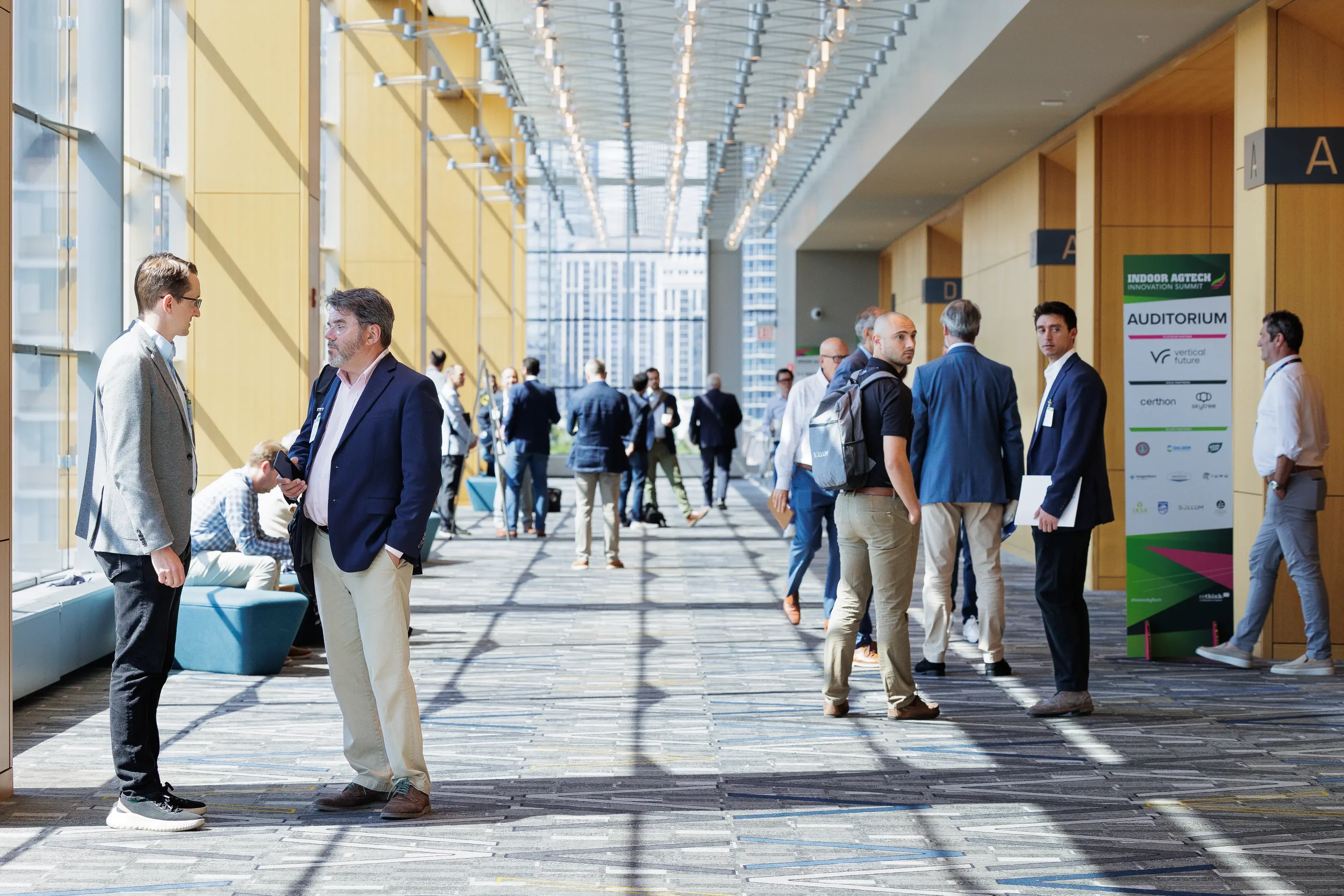 Attendees converse in conference hallway with city skyline visible at Orlando industry conference event