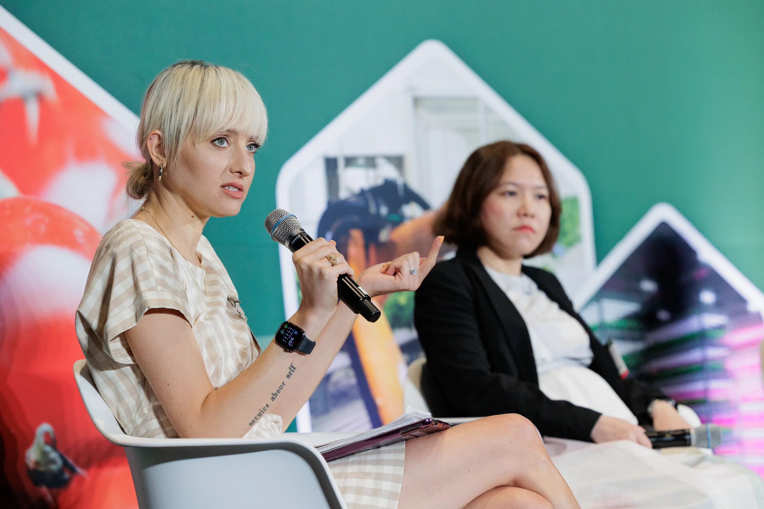 Panelist speaks into microphone while fellow speaker listens on stage at Orlando industry event