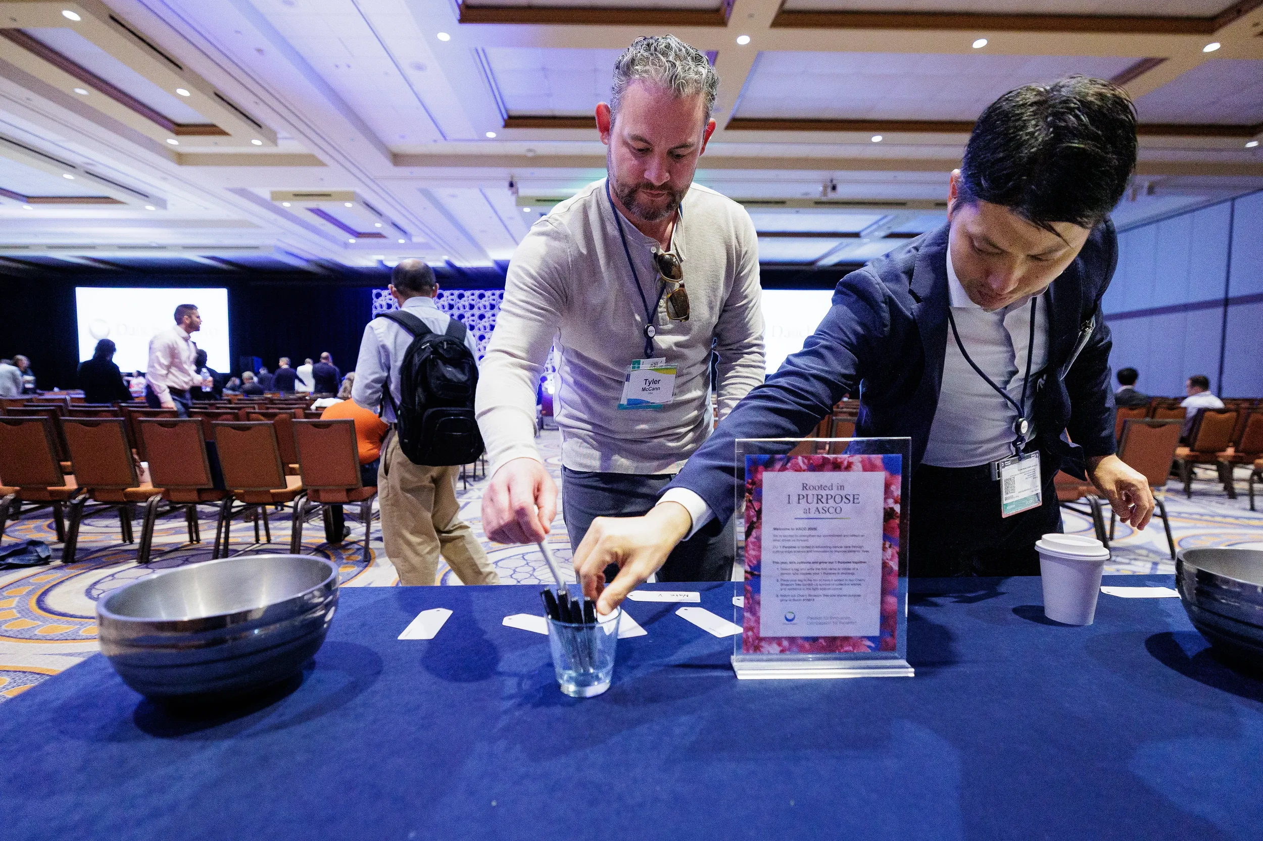 Attendees write tags at blue-draped interactive table in ballroom during Orlando corporate conference