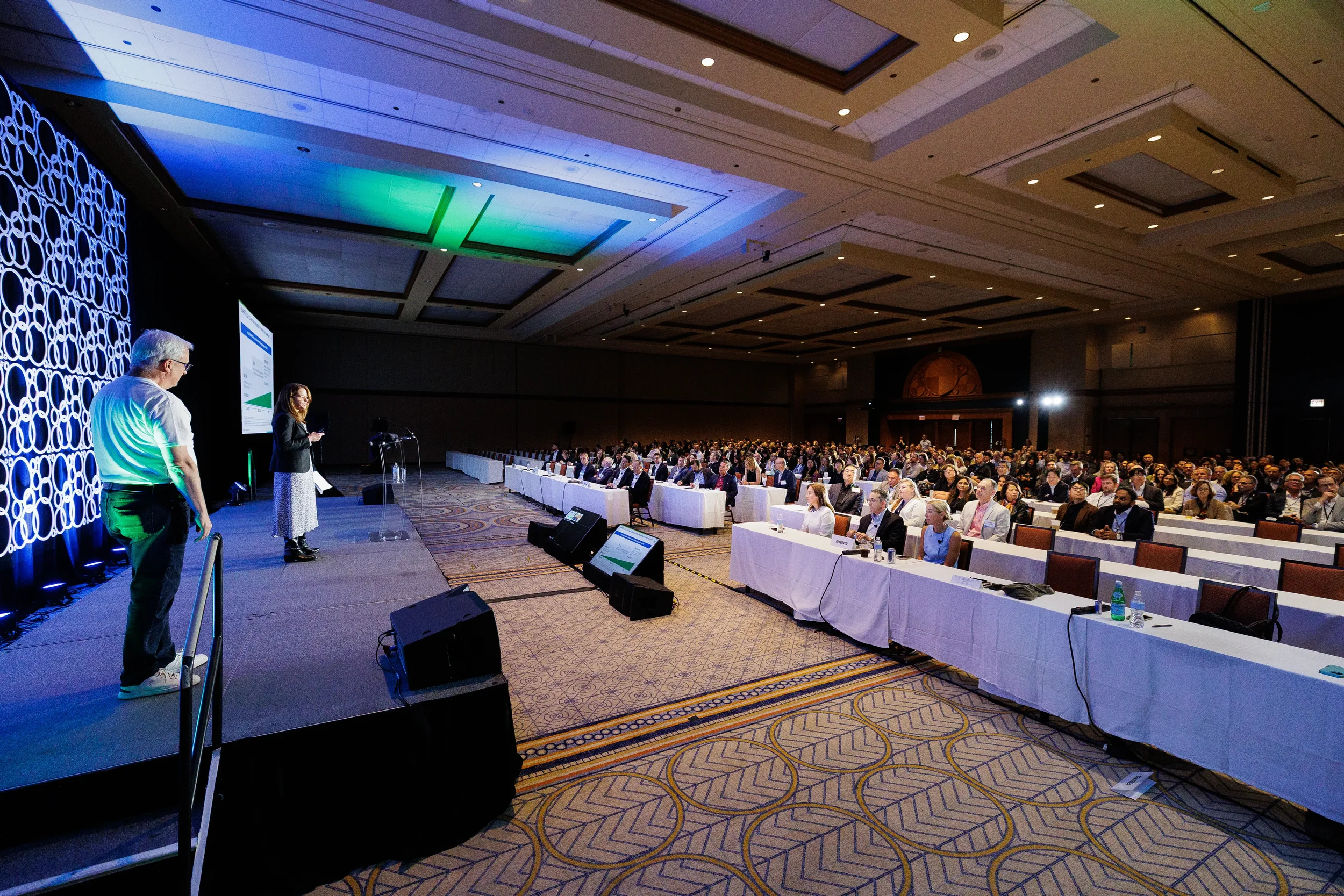 Wide view of speakers addressing seated audience in ballroom at Orlando industry conference