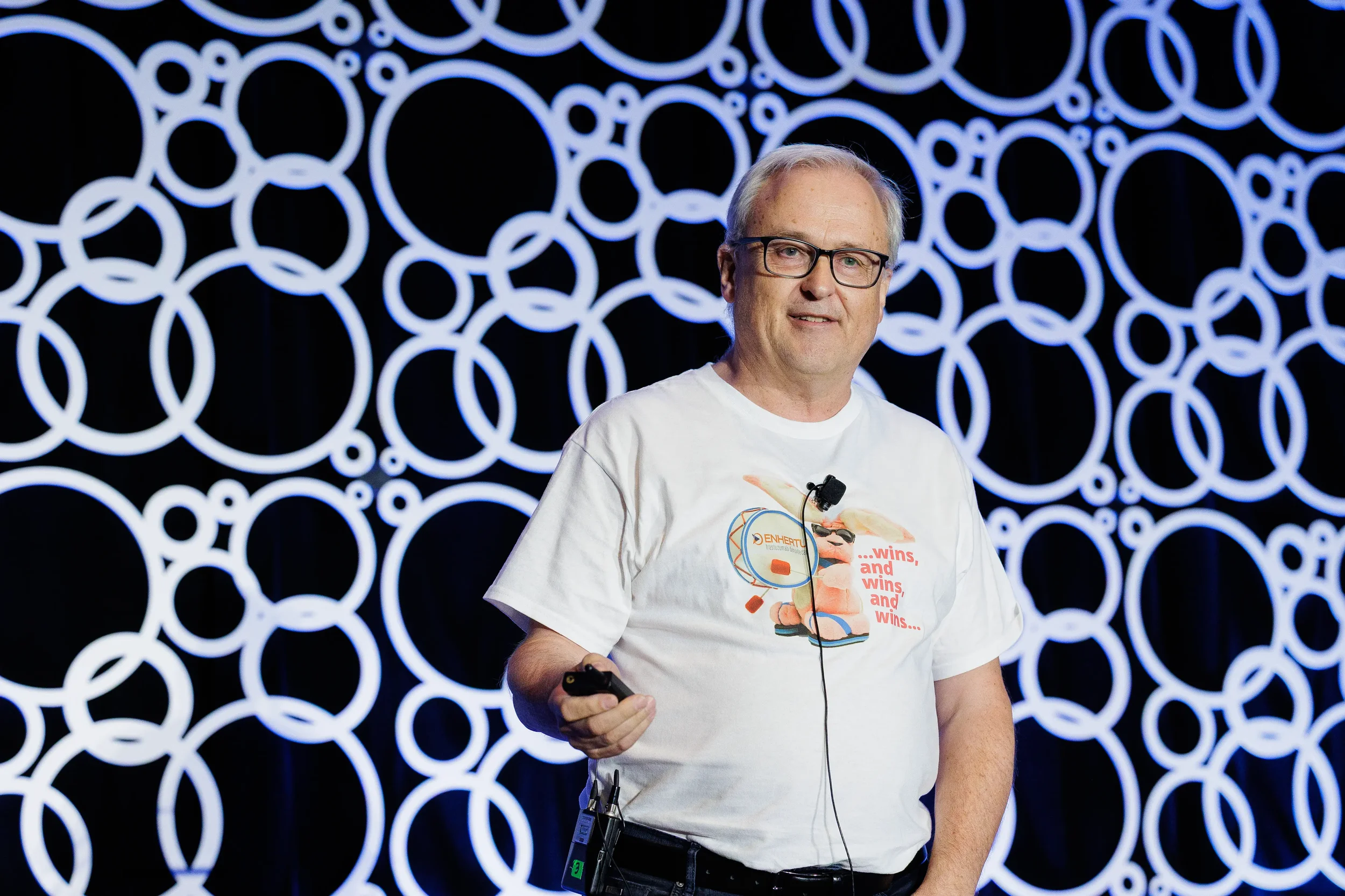 Speaker presents on stage with branded circle backdrop at Chicago corporate conference