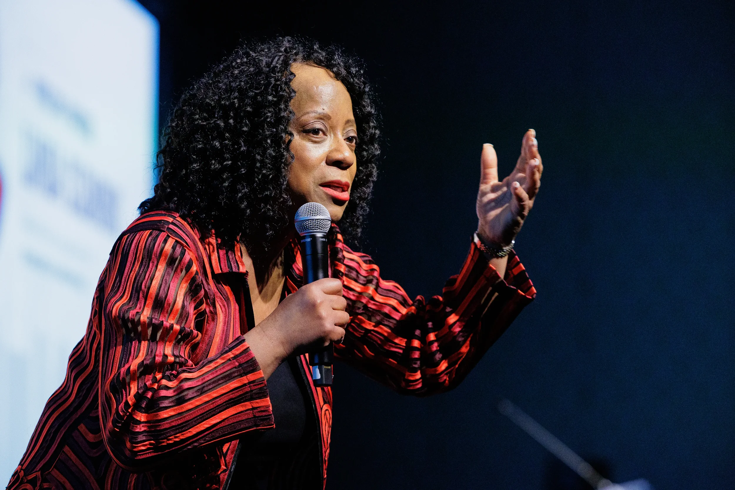 Keynote speaker gestures while addressing audience with microphone on stage at Chicago corporate event