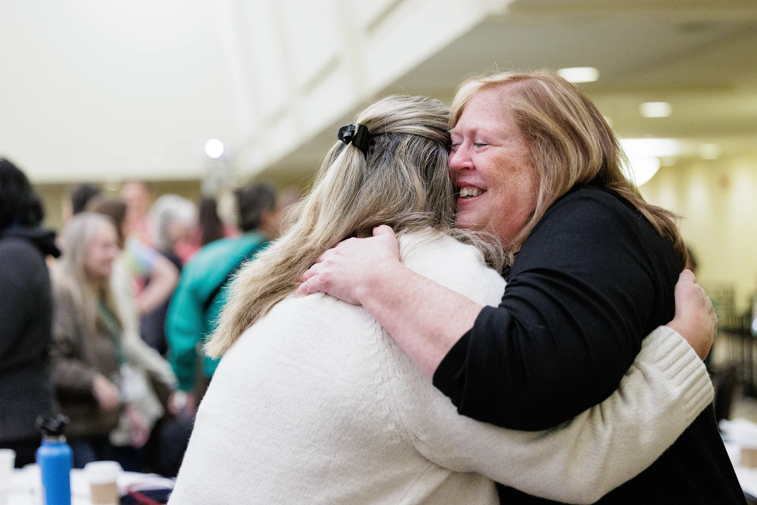 Two attendees share a warm embrace during networking break at Orlando nonprofit conference event
