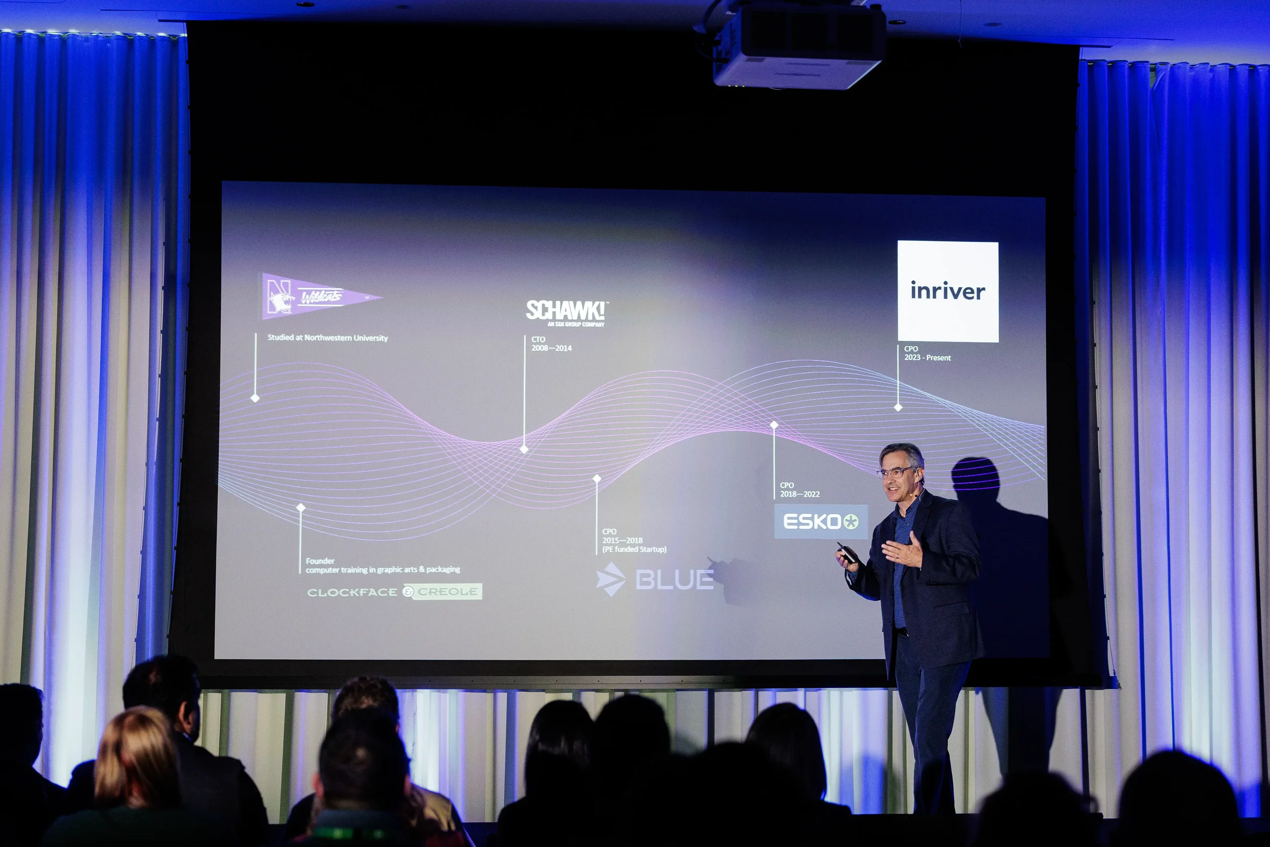 Speaker presents career timeline slide to silhouetted audience on stage at Orlando corporate conference